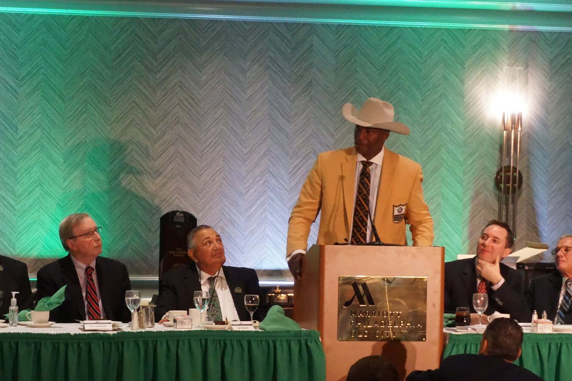 A man in a cowboy hat is standing at a podium giving a speech