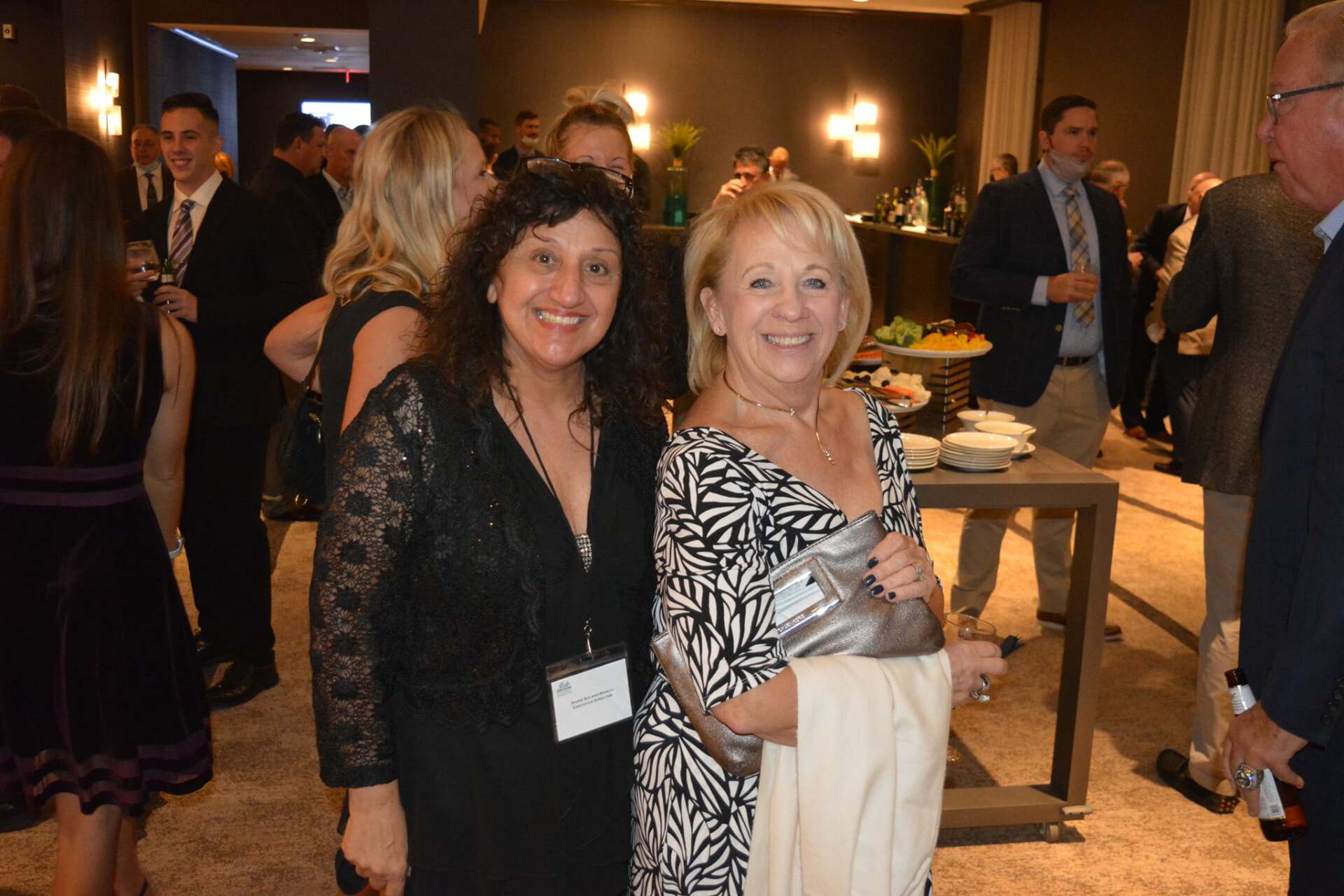 Two women are posing for a picture in a crowded room.