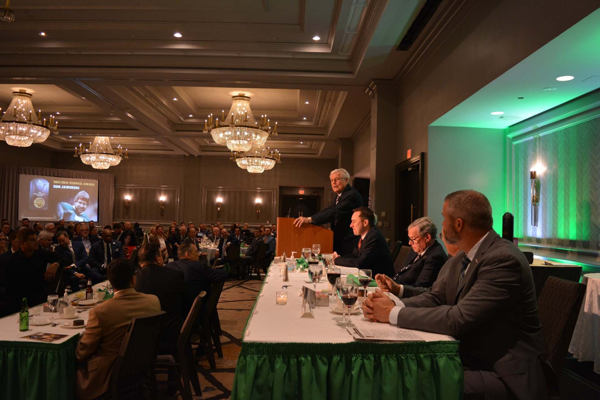 A man is giving a speech at a conference in a large room.