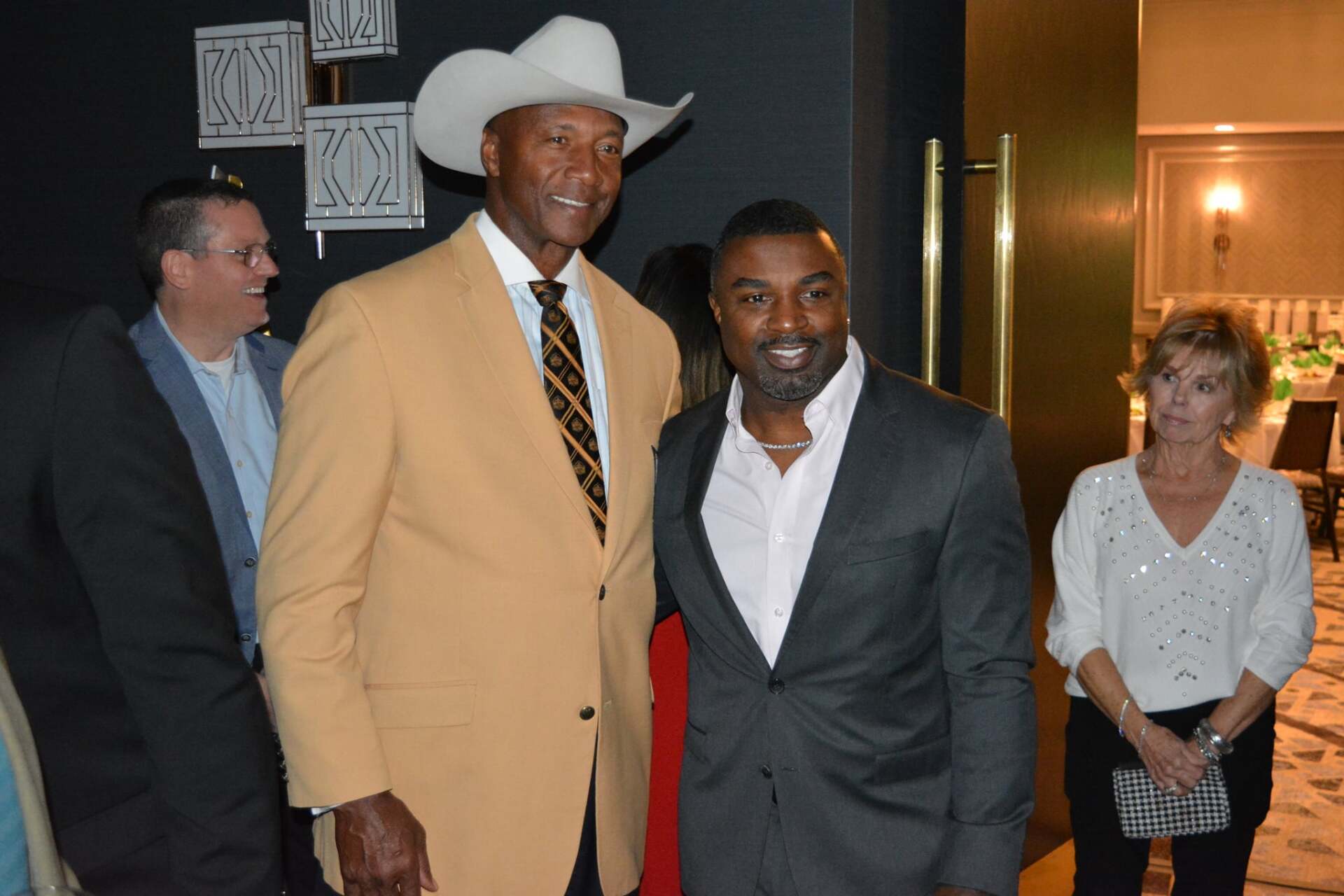 A man in a cowboy hat is standing next to another man in a suit.