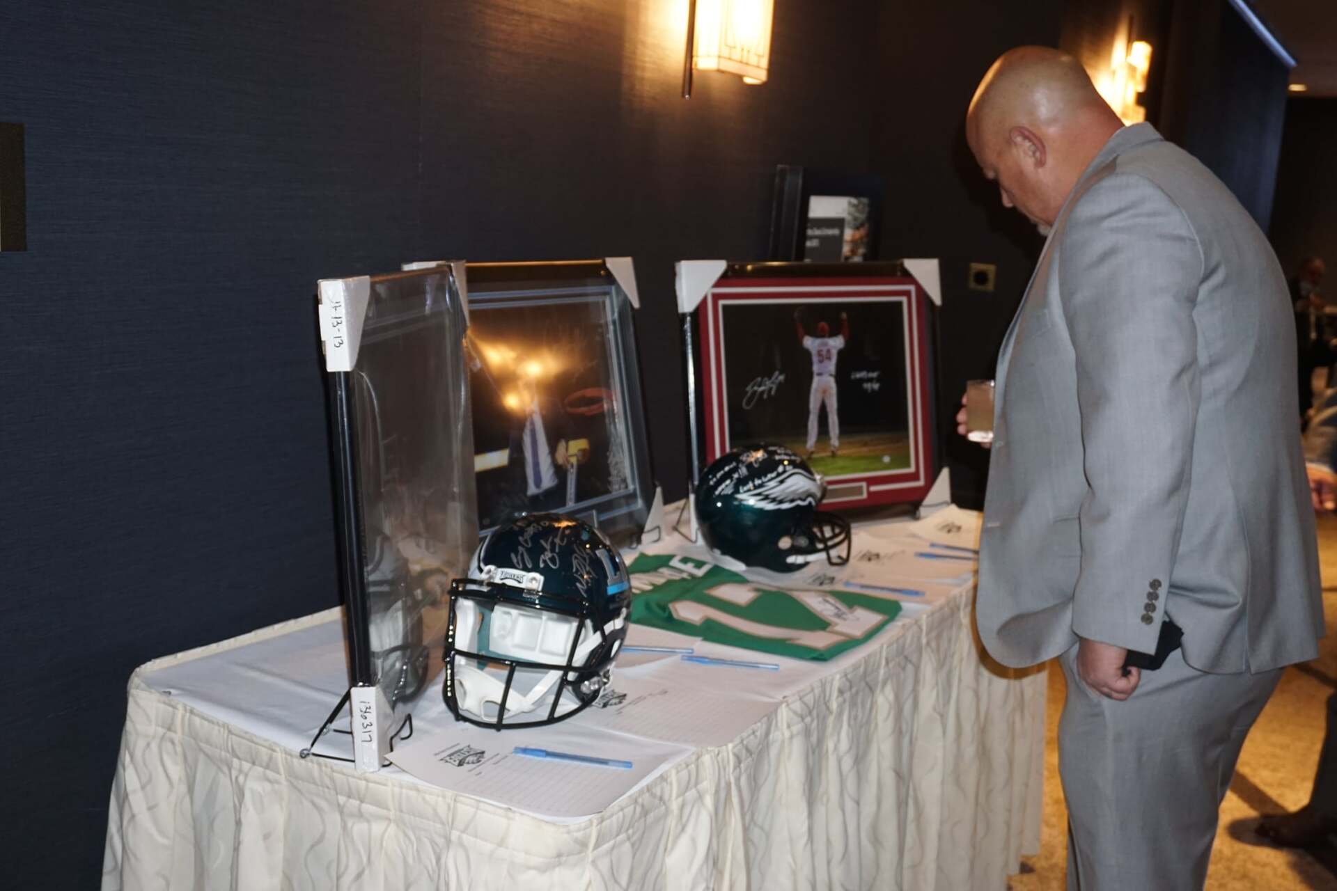 A man in a suit is looking at a table with a football helmet on it