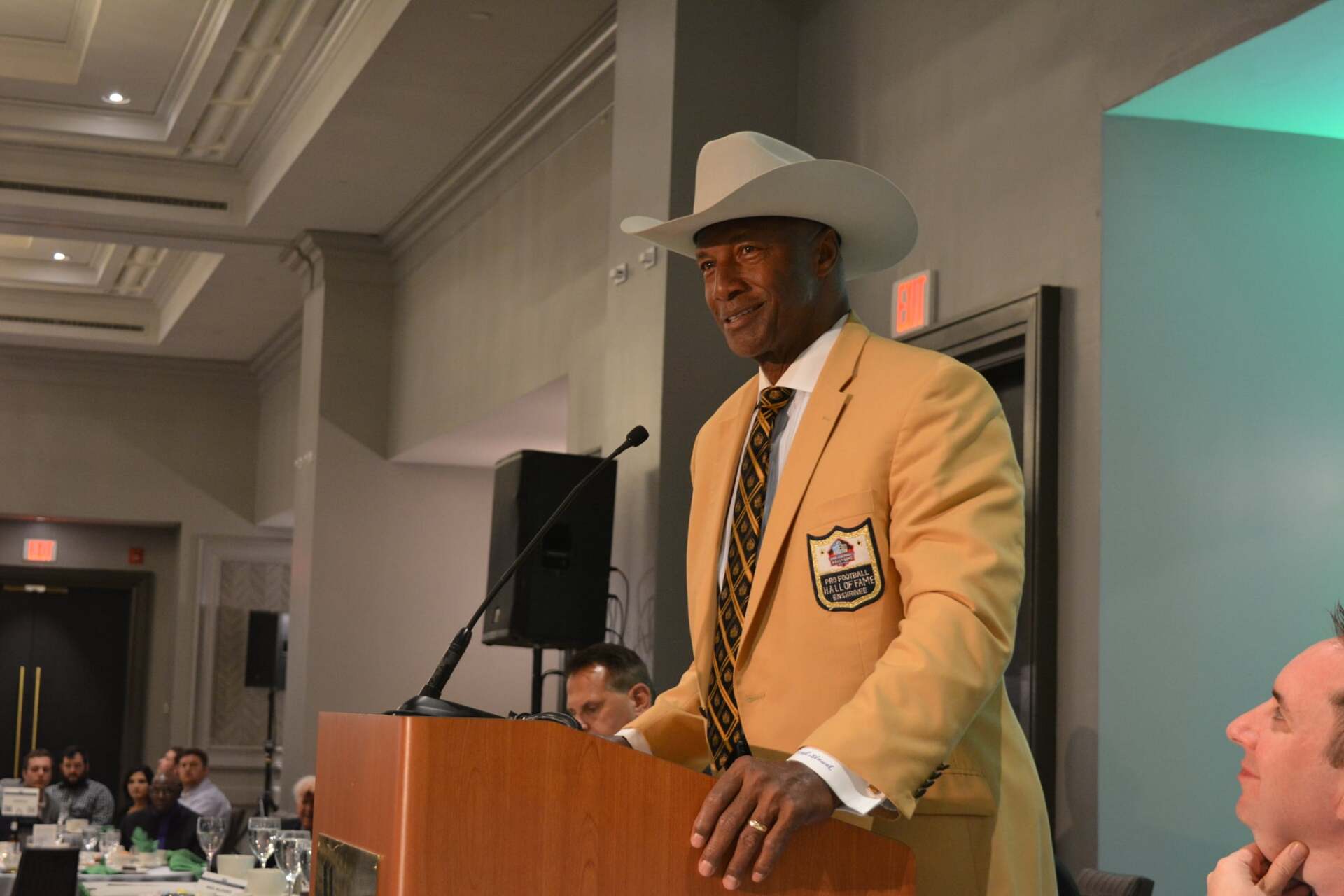 A man in a cowboy hat is standing at a podium giving a speech.