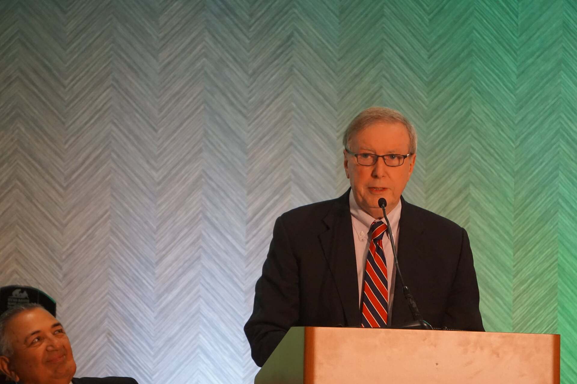 A man in a suit and tie is standing at a podium giving a speech.