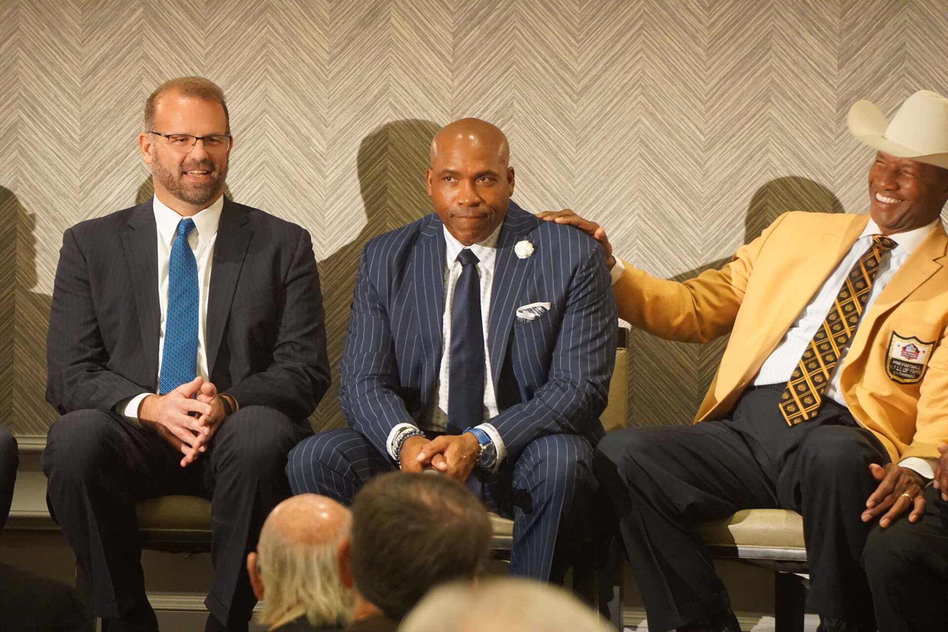 Three men in suits and ties are sitting in chairs.