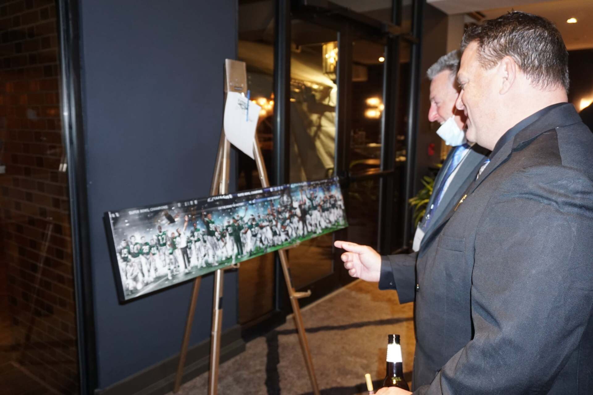 Two men are looking at a painting on an easel