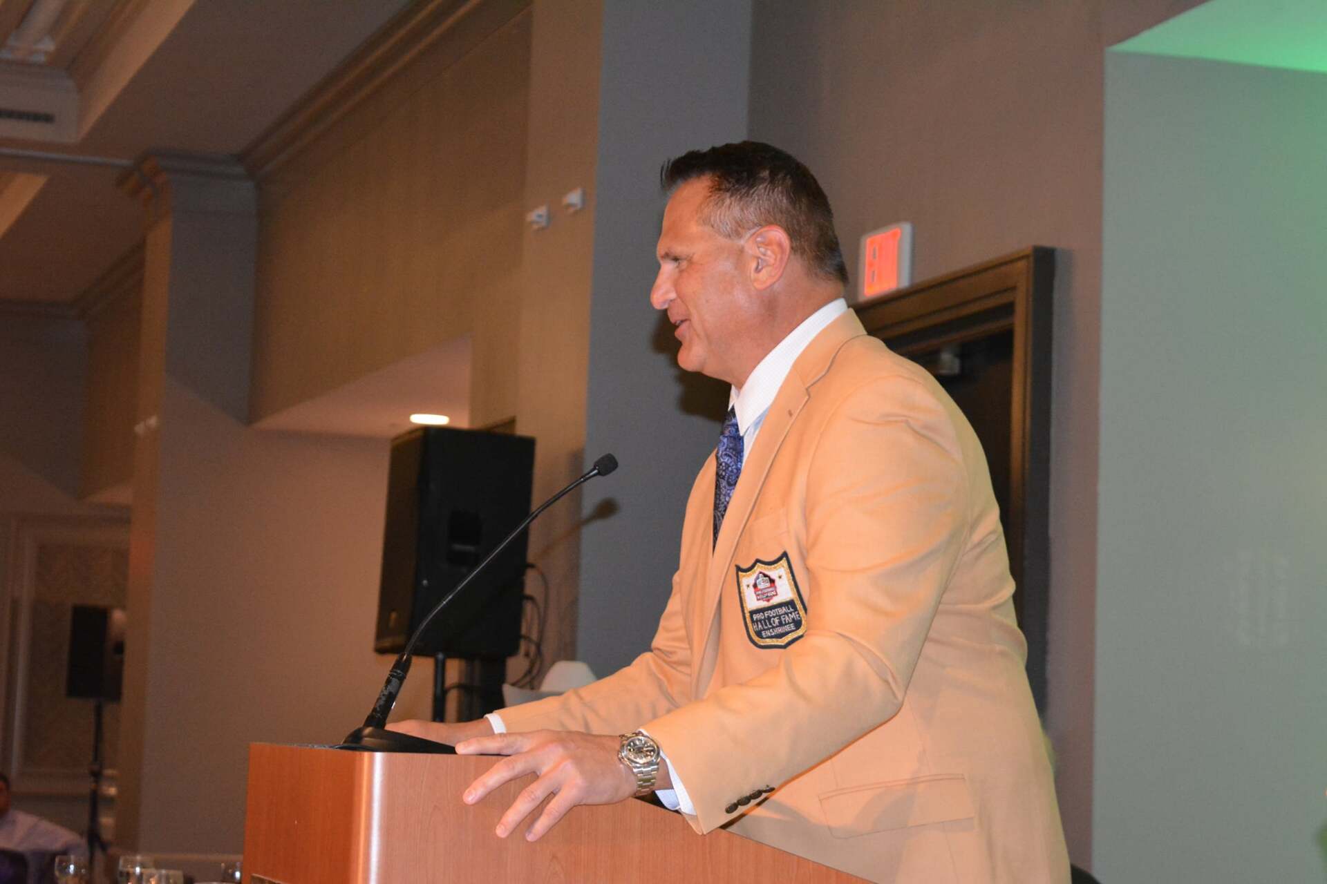 A man in a suit is standing at a podium giving a speech.