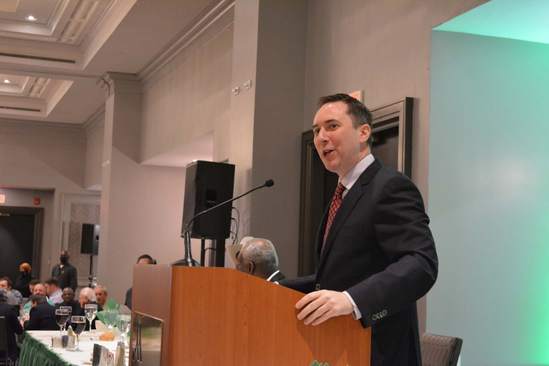 A man in a suit and tie is standing at a podium giving a speech.