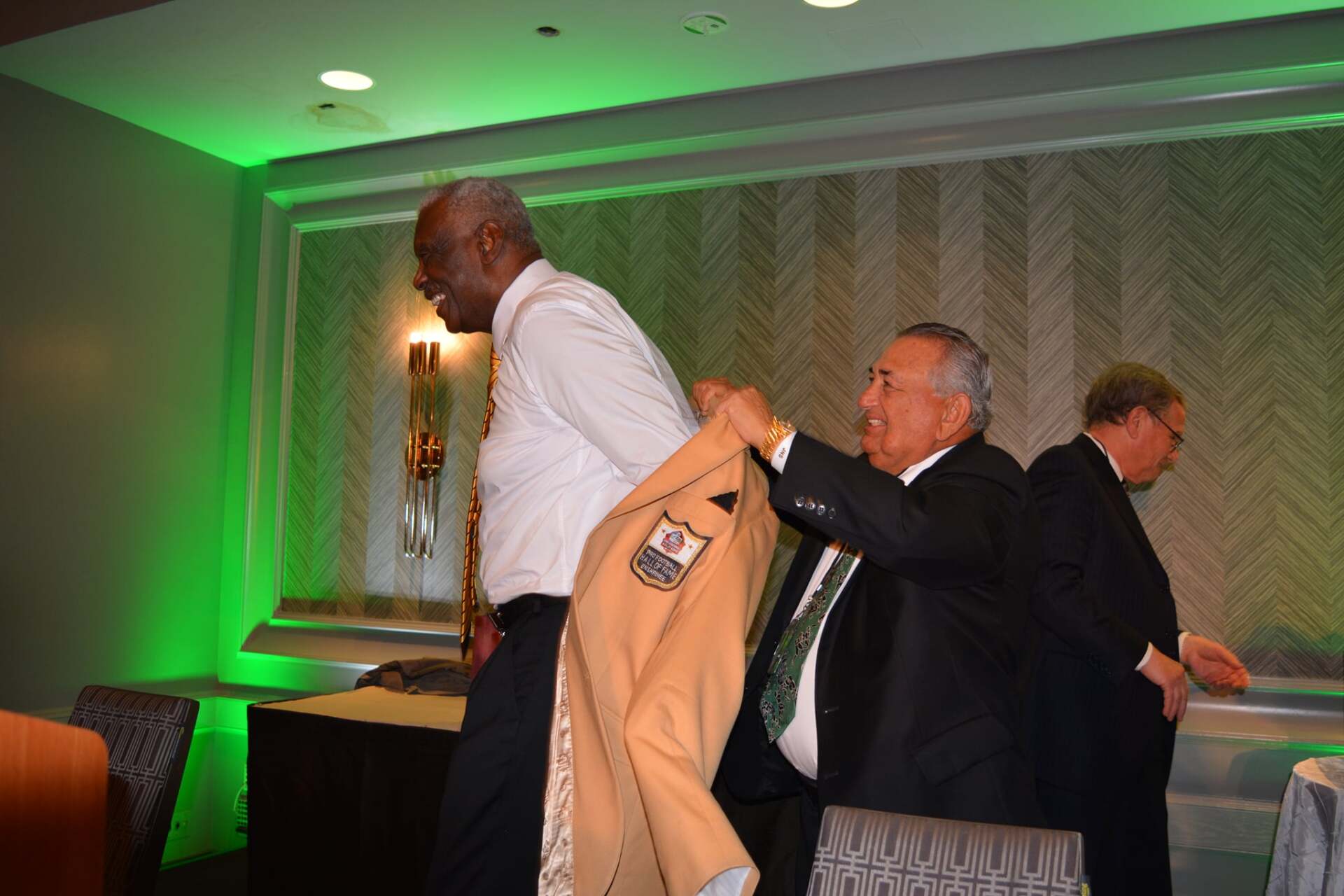 A man in a suit is helping another man with his jacket