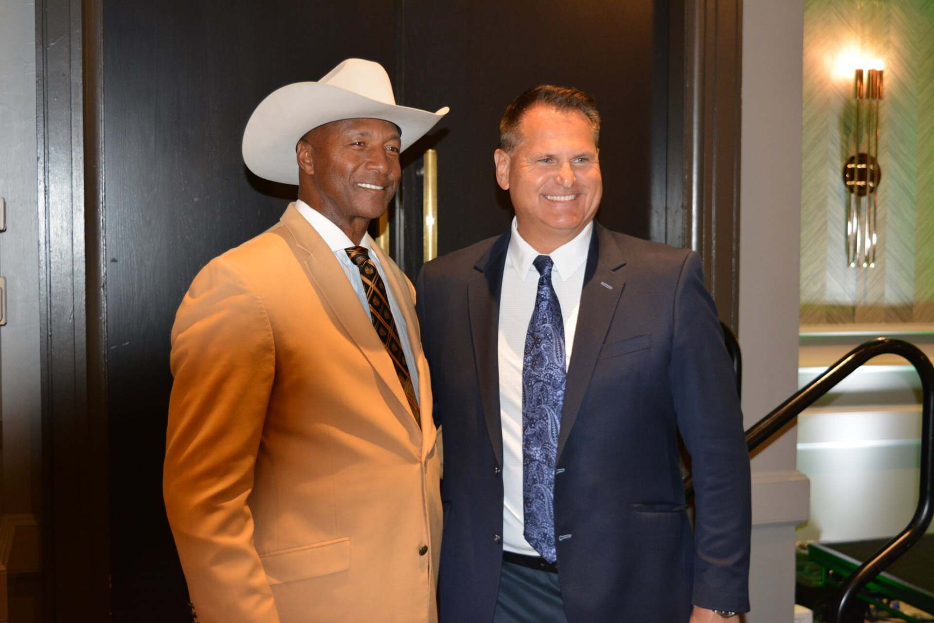 Two men in suits and cowboy hats are posing for a picture.