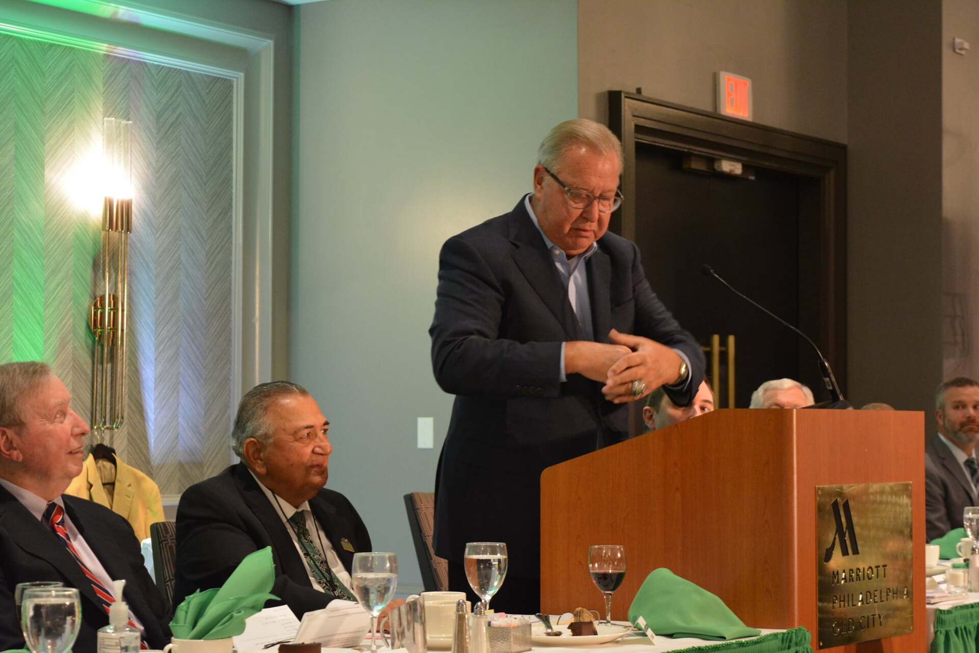 A man in a suit is standing at a podium giving a speech.