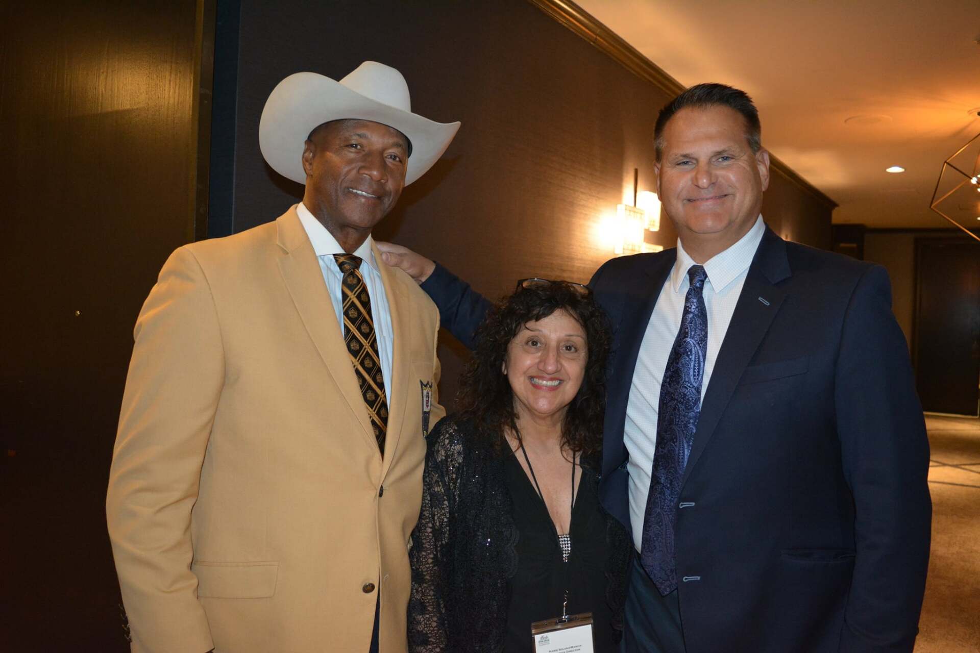 A man in a cowboy hat is standing next to two other men in suits and ties.