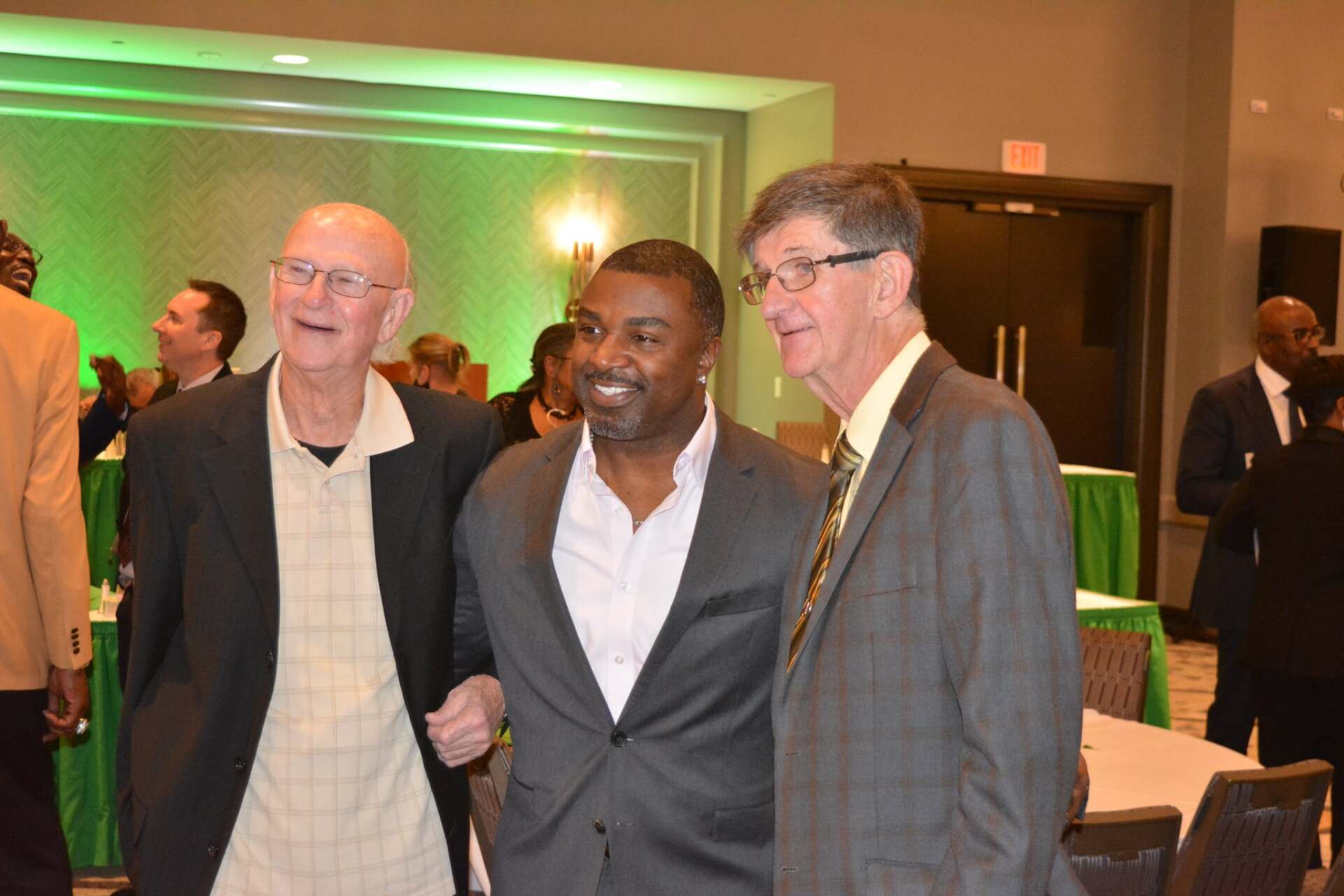 Three men in suits are standing next to each other in a room.