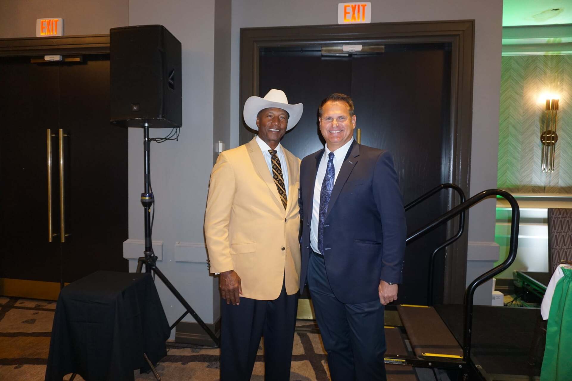 Two men in suits and cowboy hats are standing next to each other in a room.