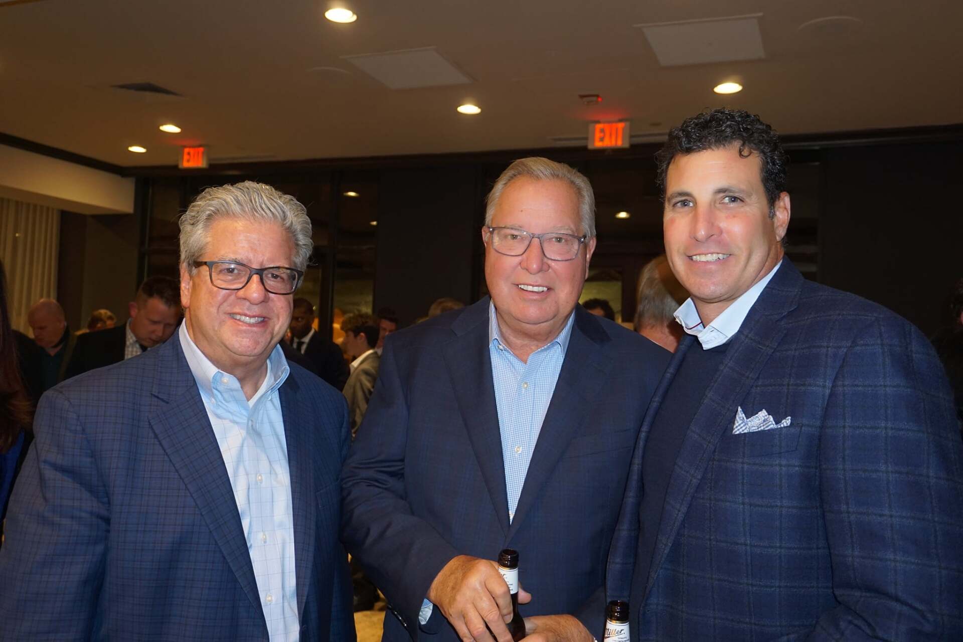 Three men in suits are posing for a picture in a room.