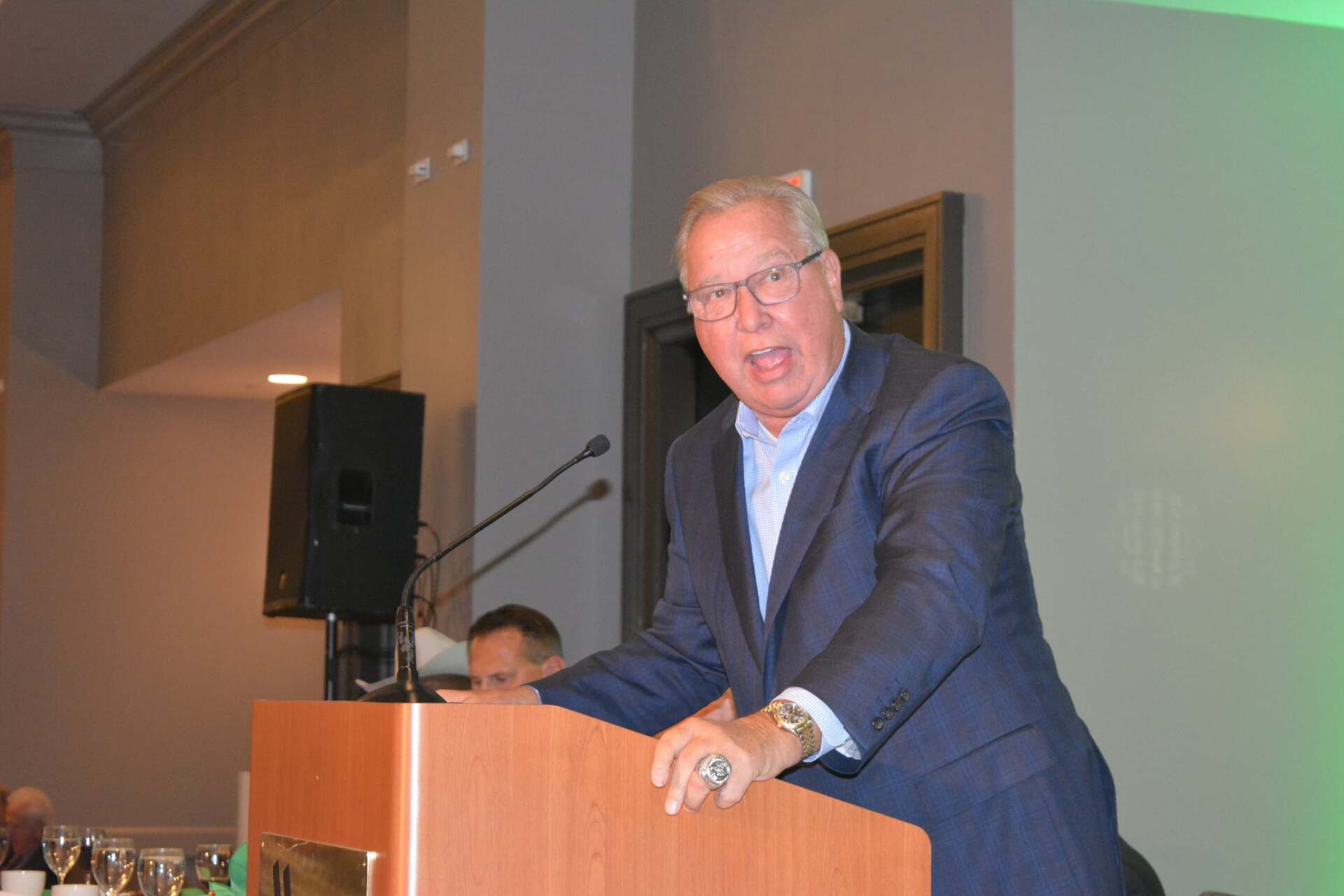 A man in a suit is standing at a podium giving a speech.
