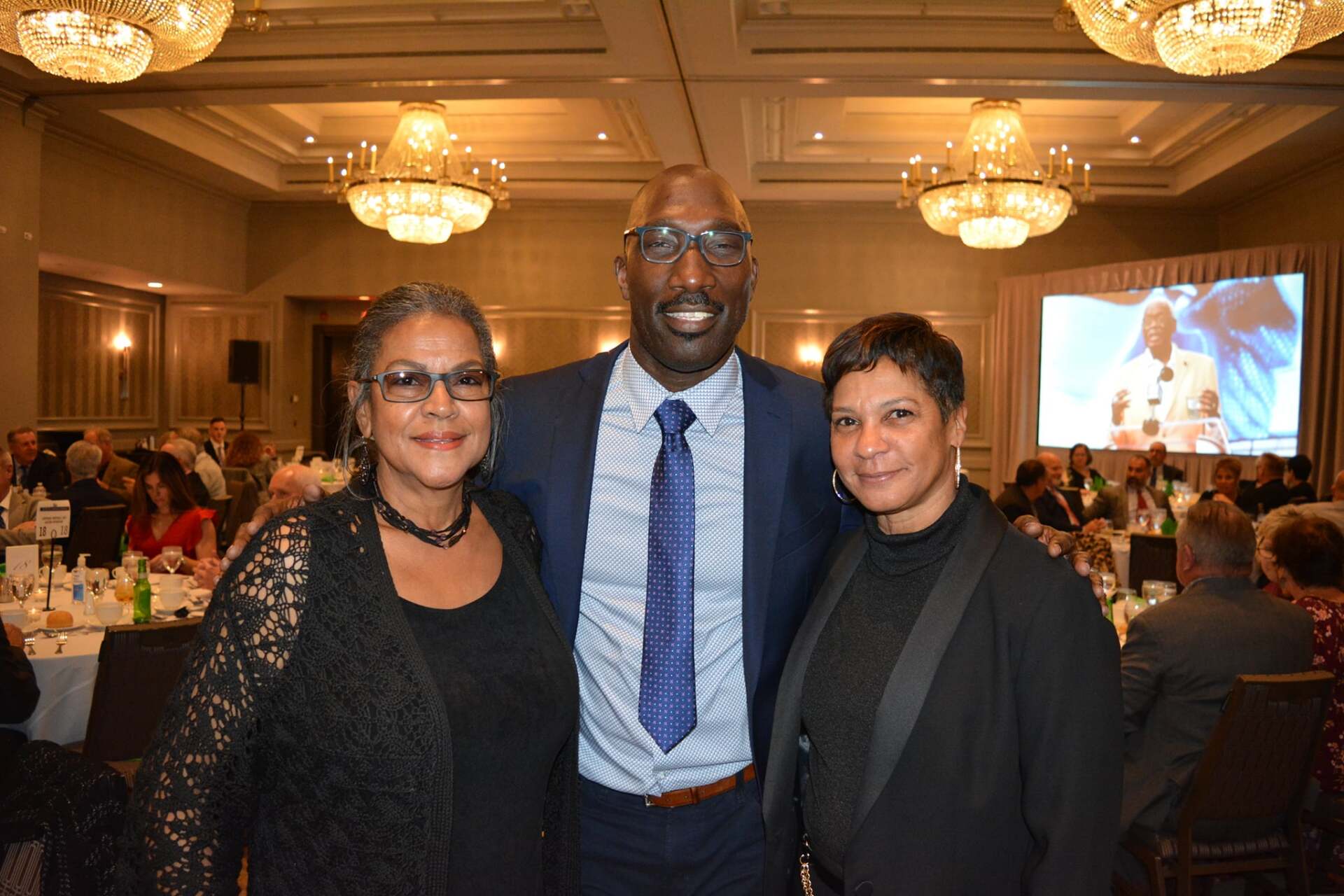 A man in a suit and tie is posing for a picture with two women.