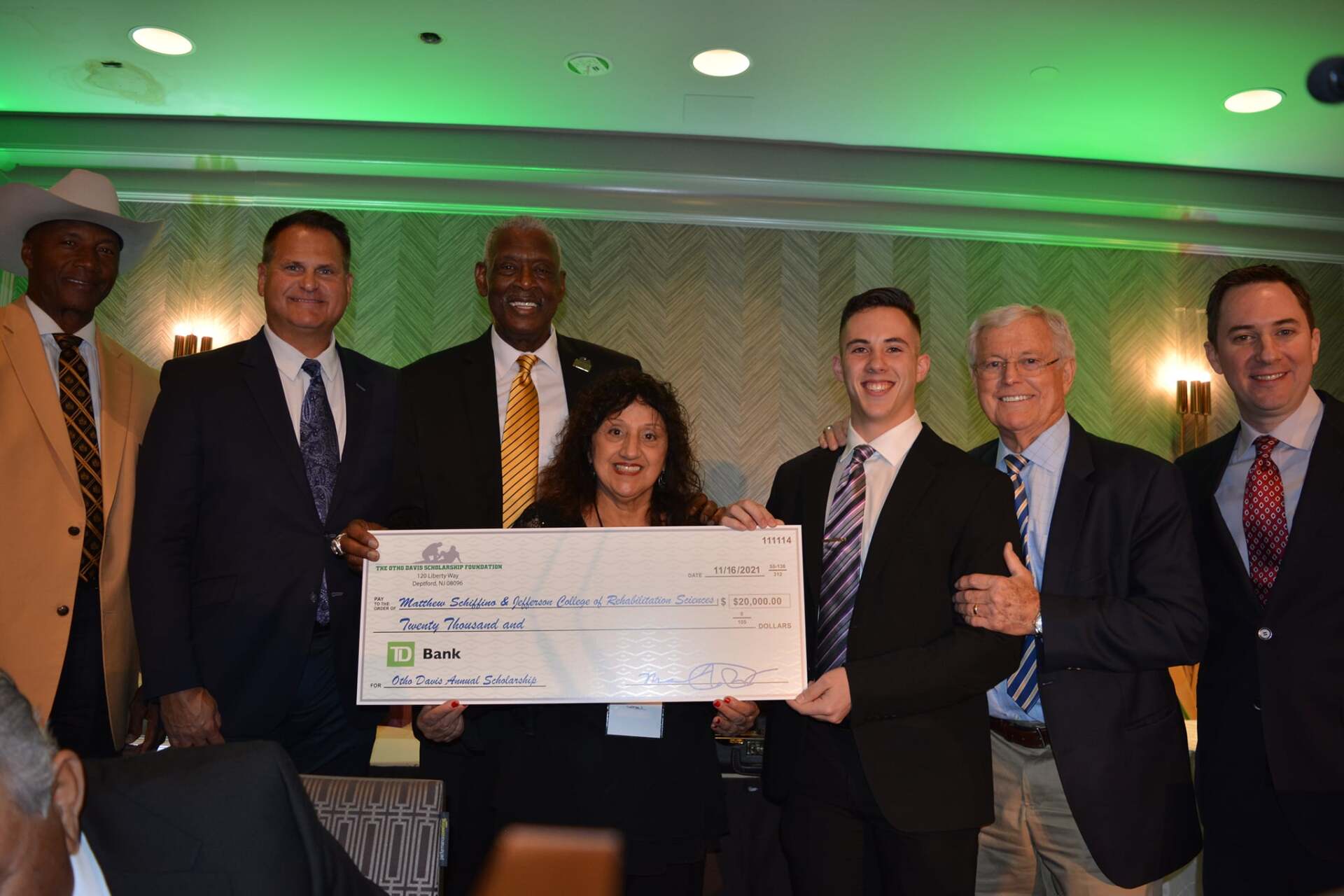 A group of men and women are posing for a picture while holding a large check.