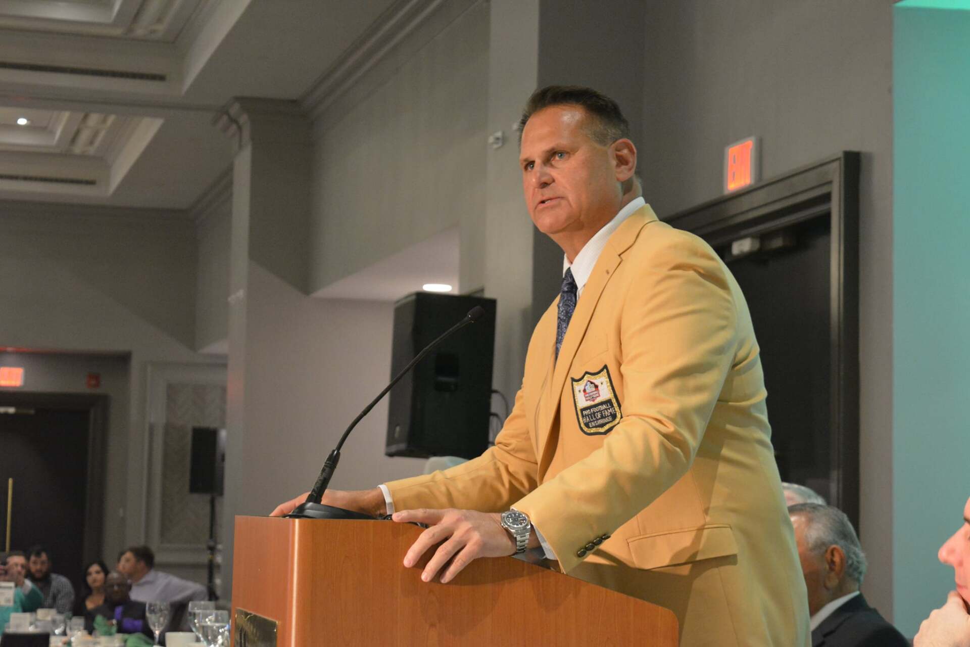 A man in a suit is standing at a podium giving a speech.