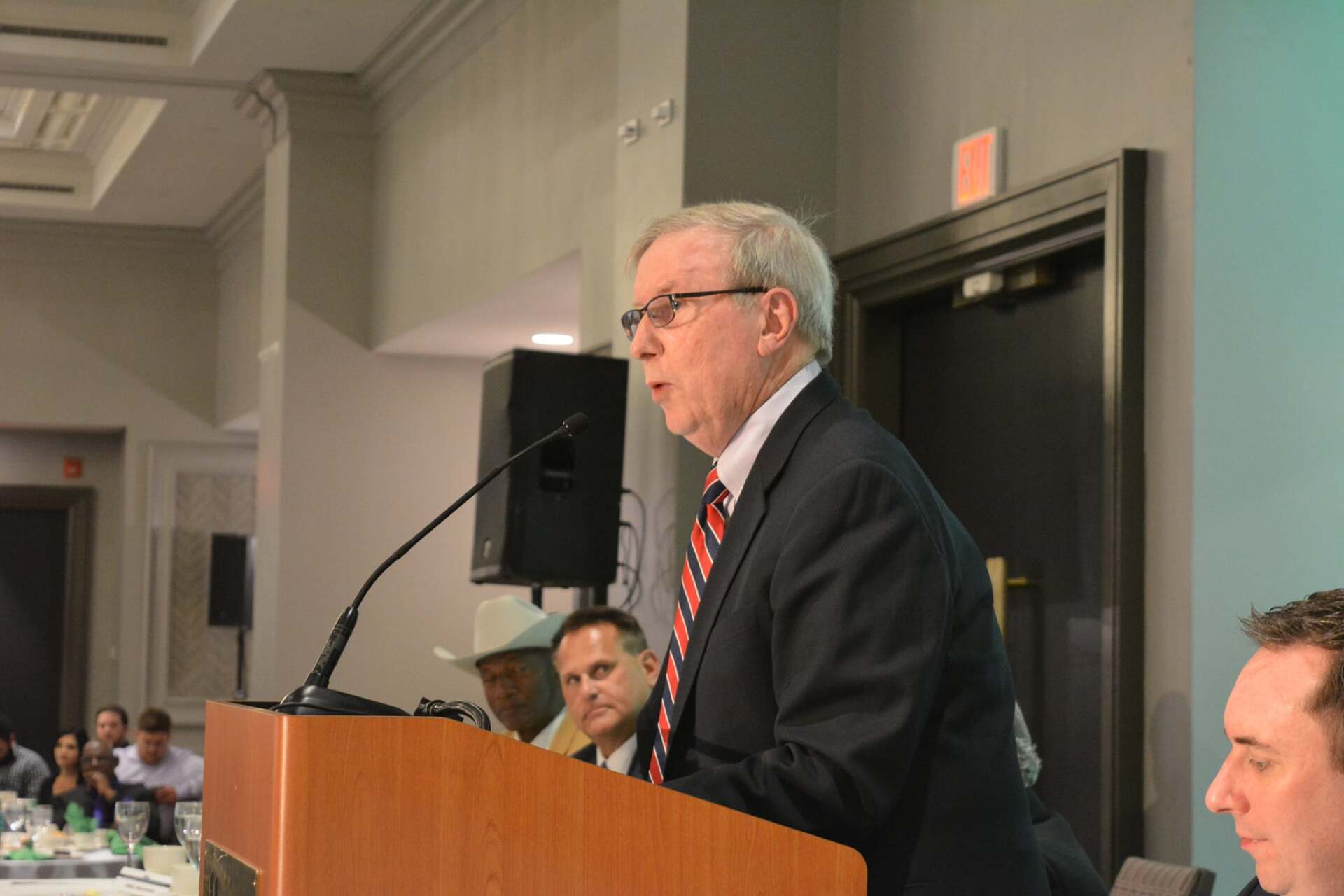 A man in a suit and tie is giving a speech at a podium