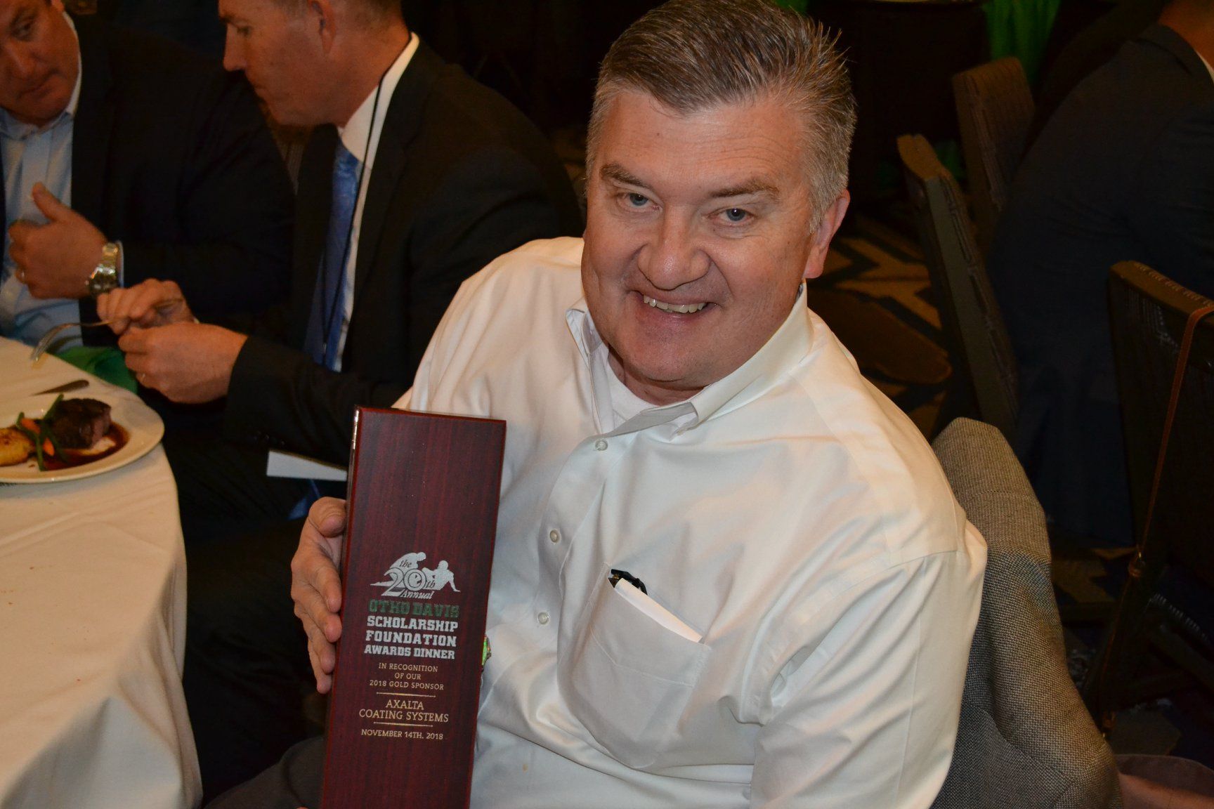 A man in a white shirt is sitting at a table holding a menu.