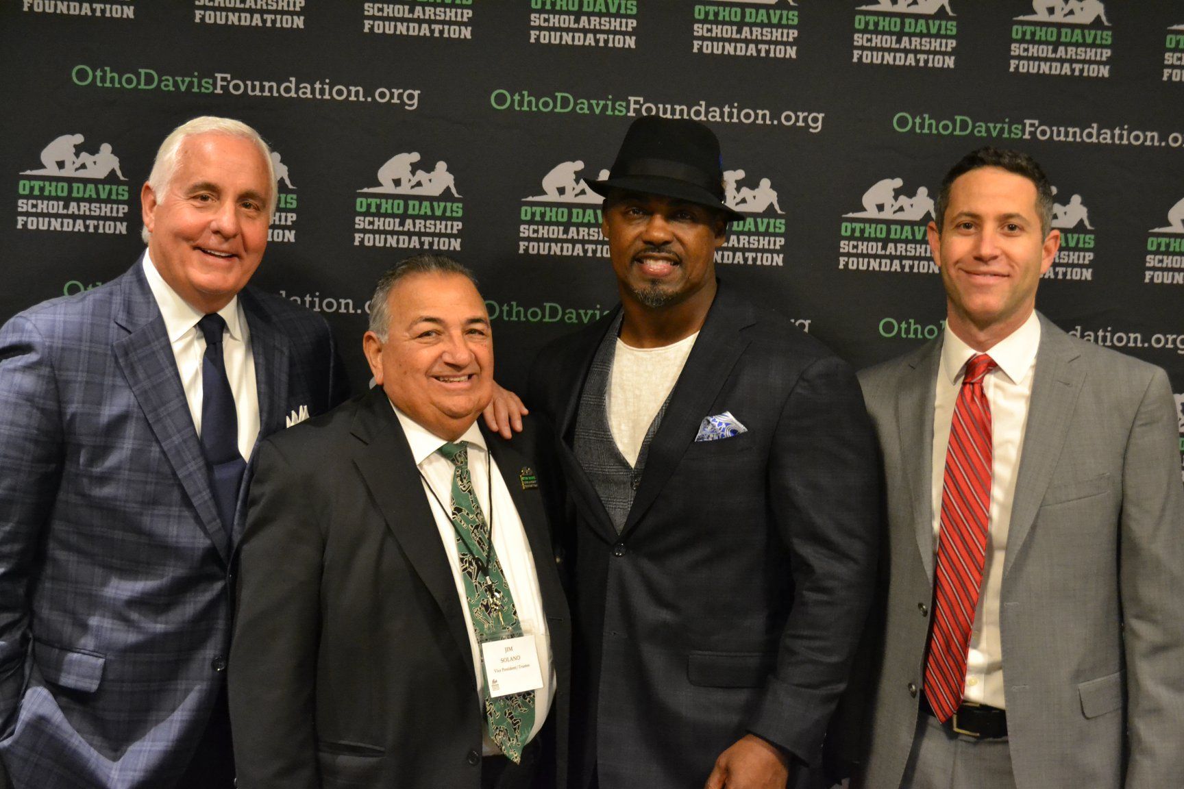 Four men in suits and ties pose for a picture