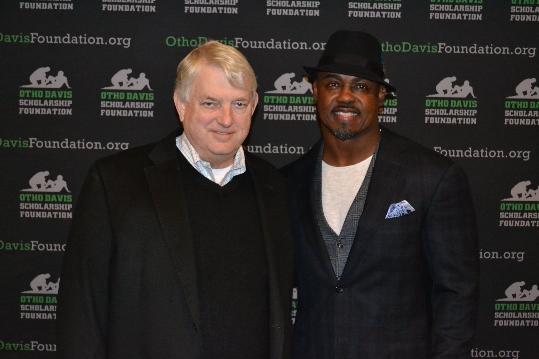 Two men are posing for a picture in front of a wall that says the davis foundation