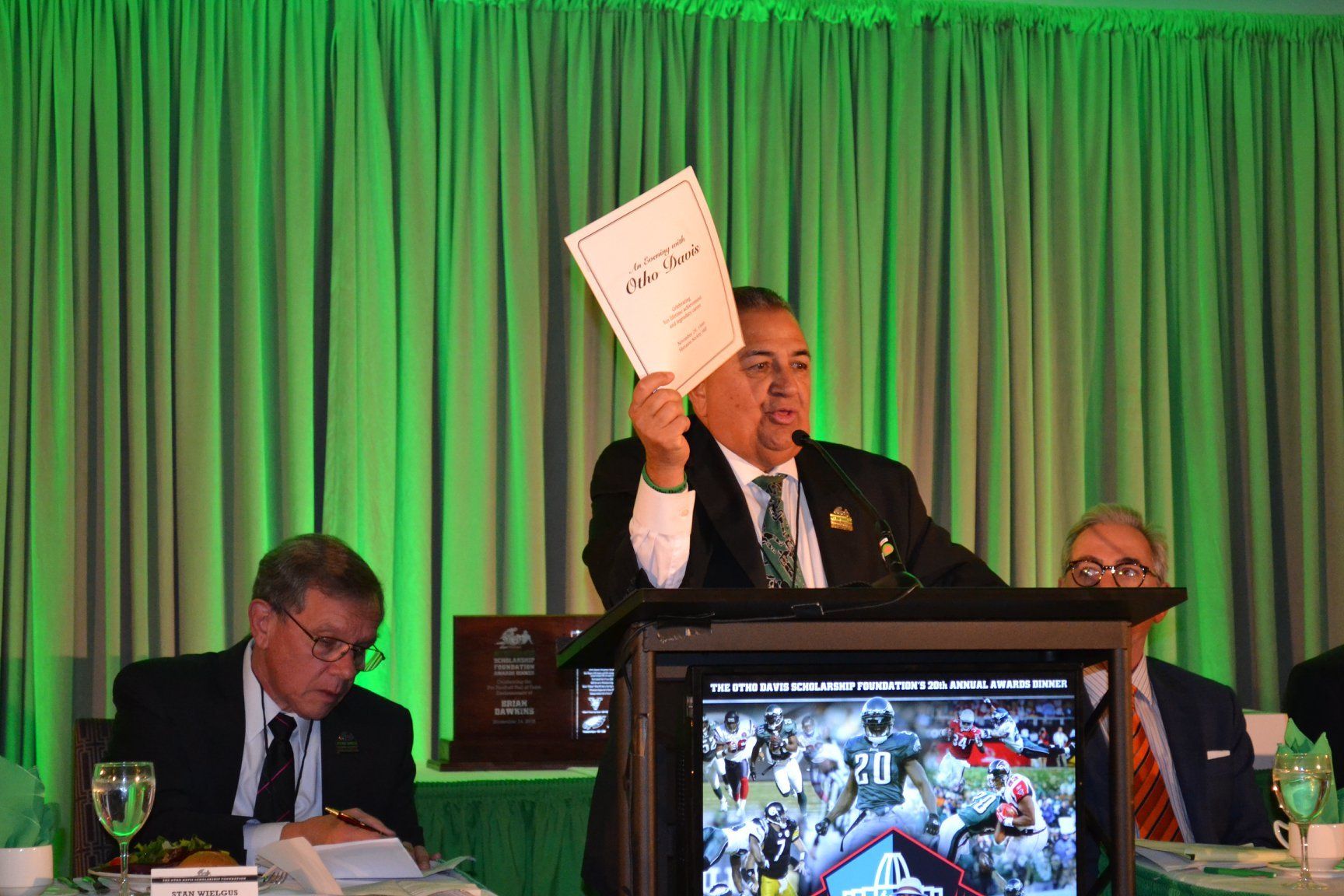 A man is standing at a podium holding a piece of paper.
