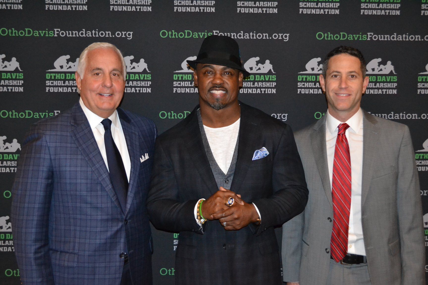 Four men in suits and ties are posing for a picture