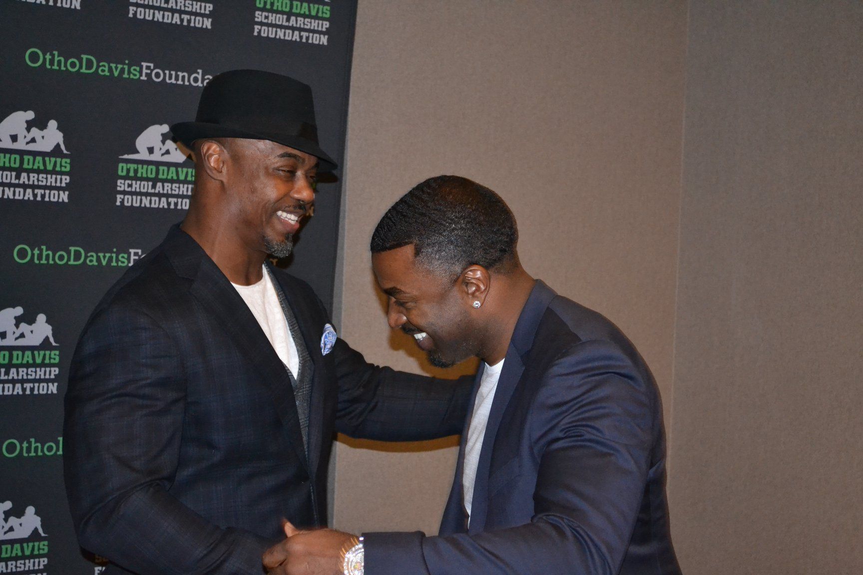 Two men shaking hands in front of a wall that says ortho davis