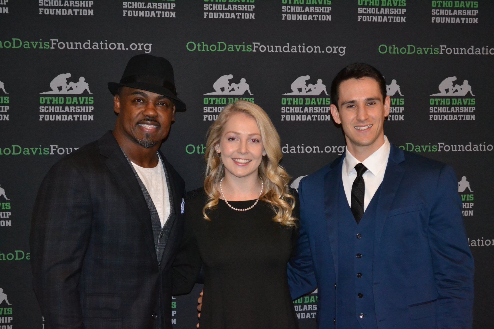 A man and two women are posing for a picture in front of a wall that says foundation.org