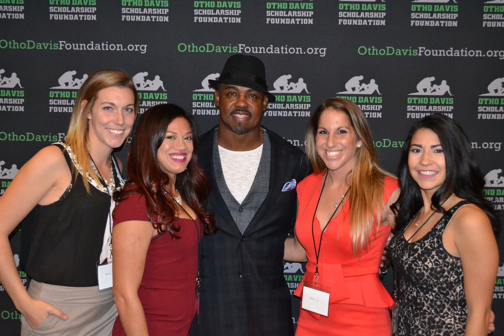 A group of women are posing for a picture with a man in a hat