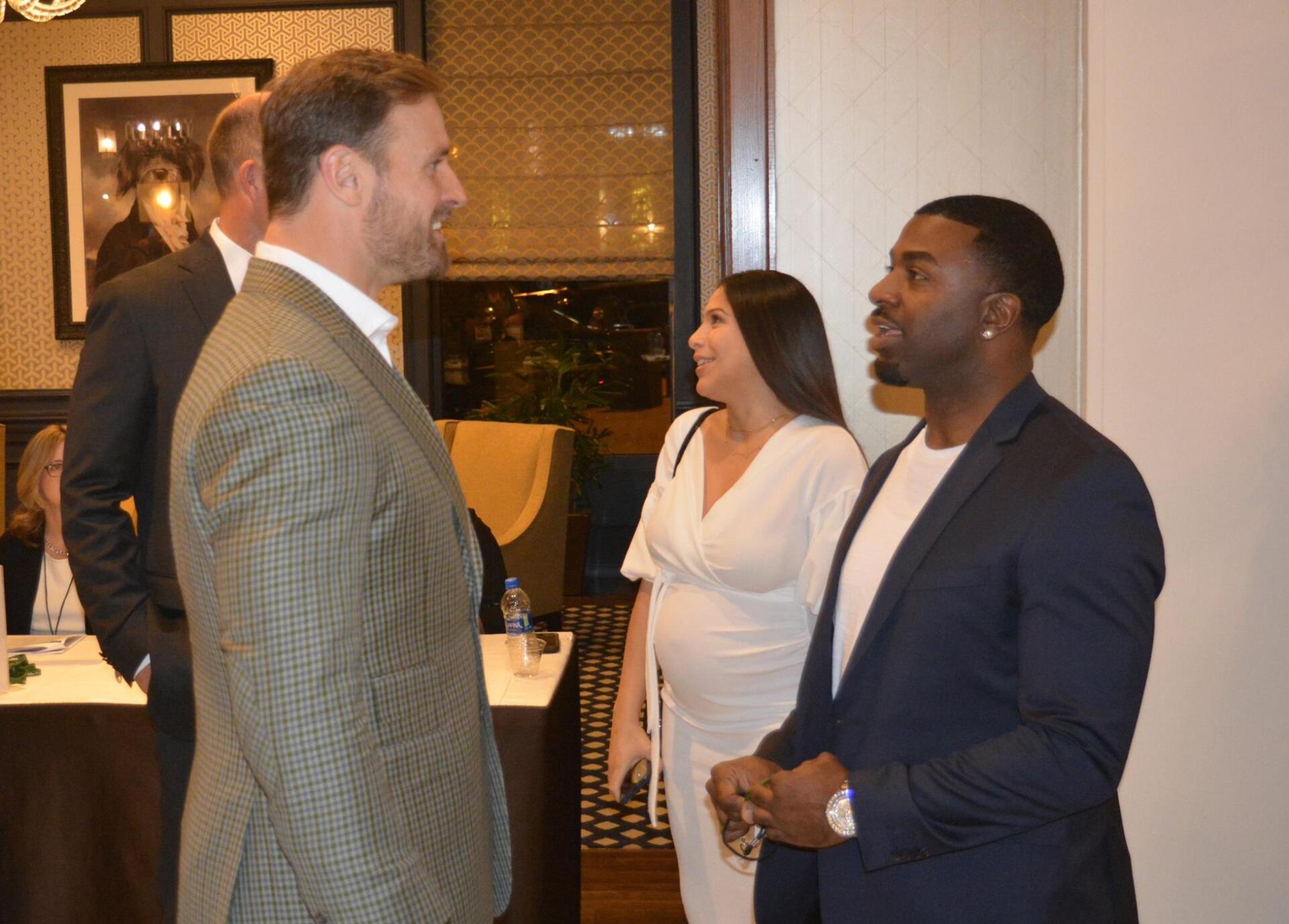 A group of people are standing in a room talking to each other.