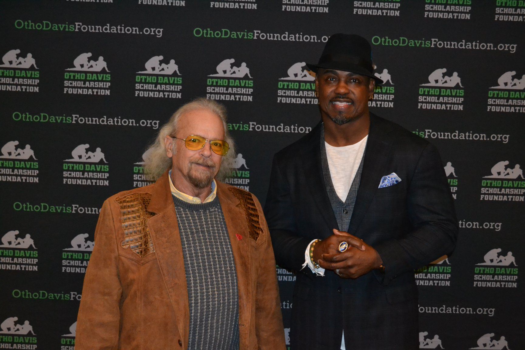 Two men are posing for a picture in front of a wall that says ohiodavidfoundation.org