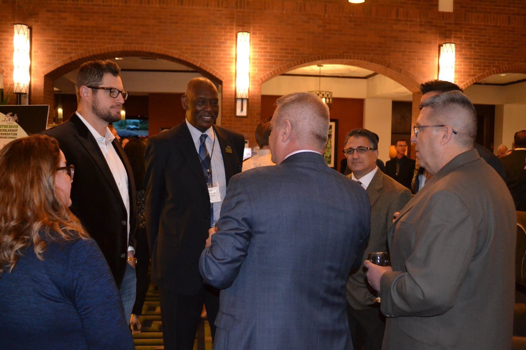 A group of people are standing in a room talking to each other.