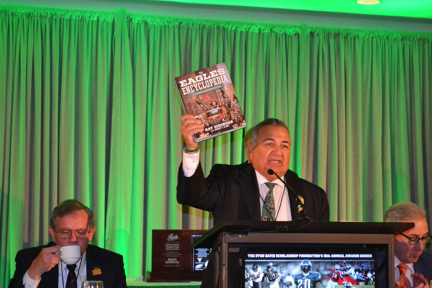 A man is standing at a podium holding a book.