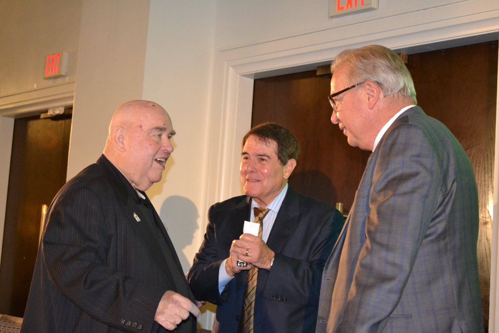 Three men in suits are talking to each other in a room.
