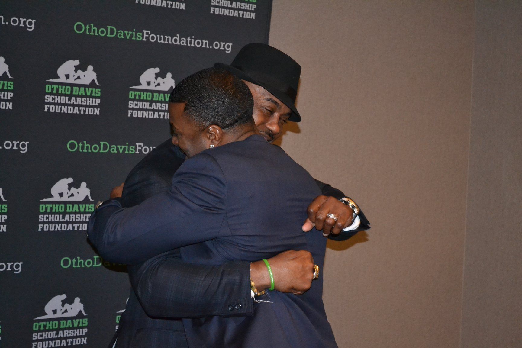 Two men hugging in front of a ohio davis foundation sign