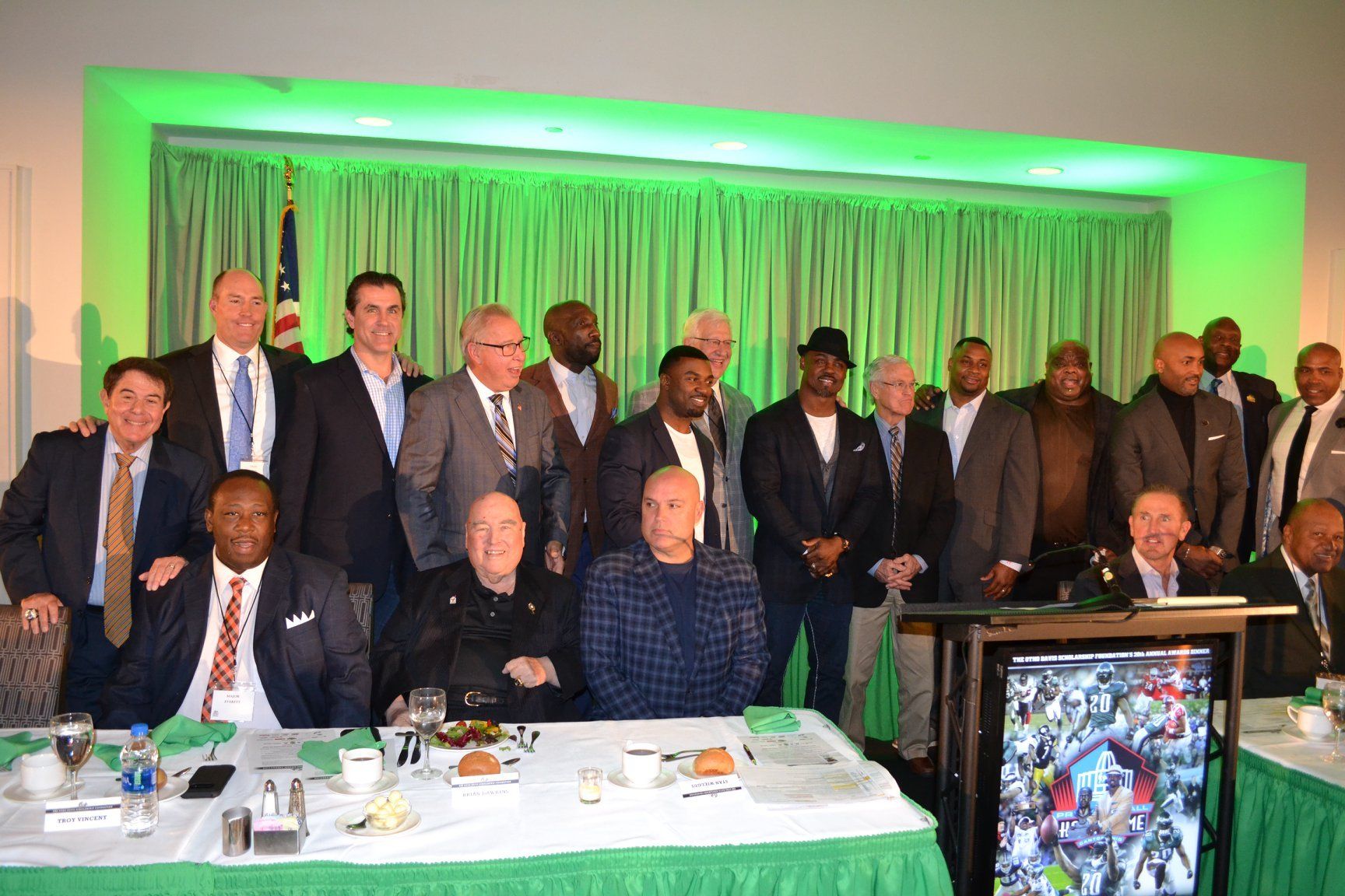 A group of men are posing for a picture while sitting at a table.