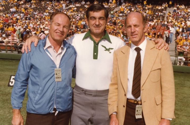 Three men are posing for a picture with the number 5 in the background