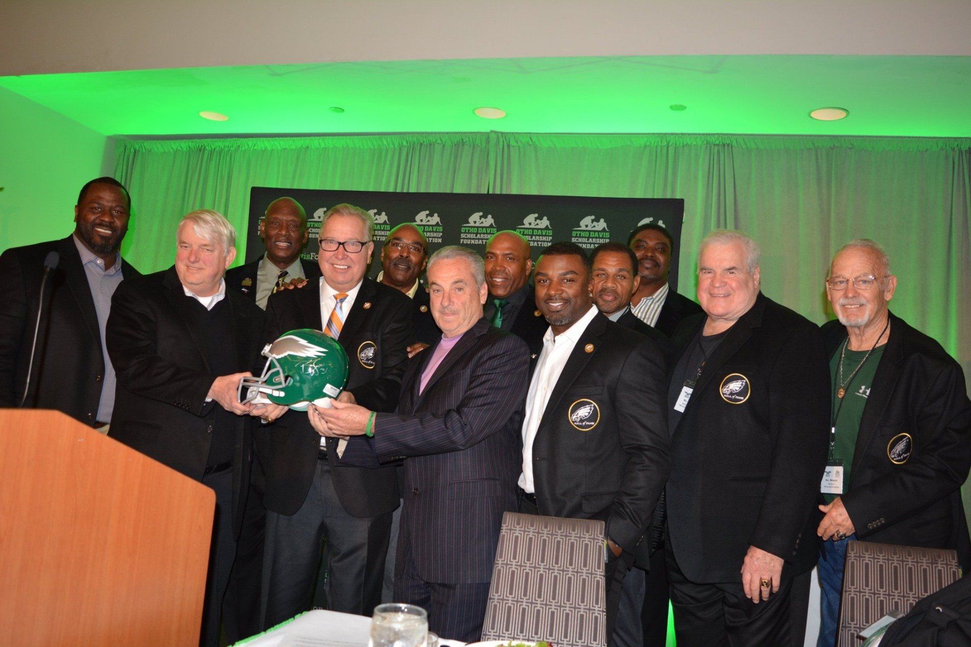 A group of men are posing for a picture and one of them is holding a helmet.
