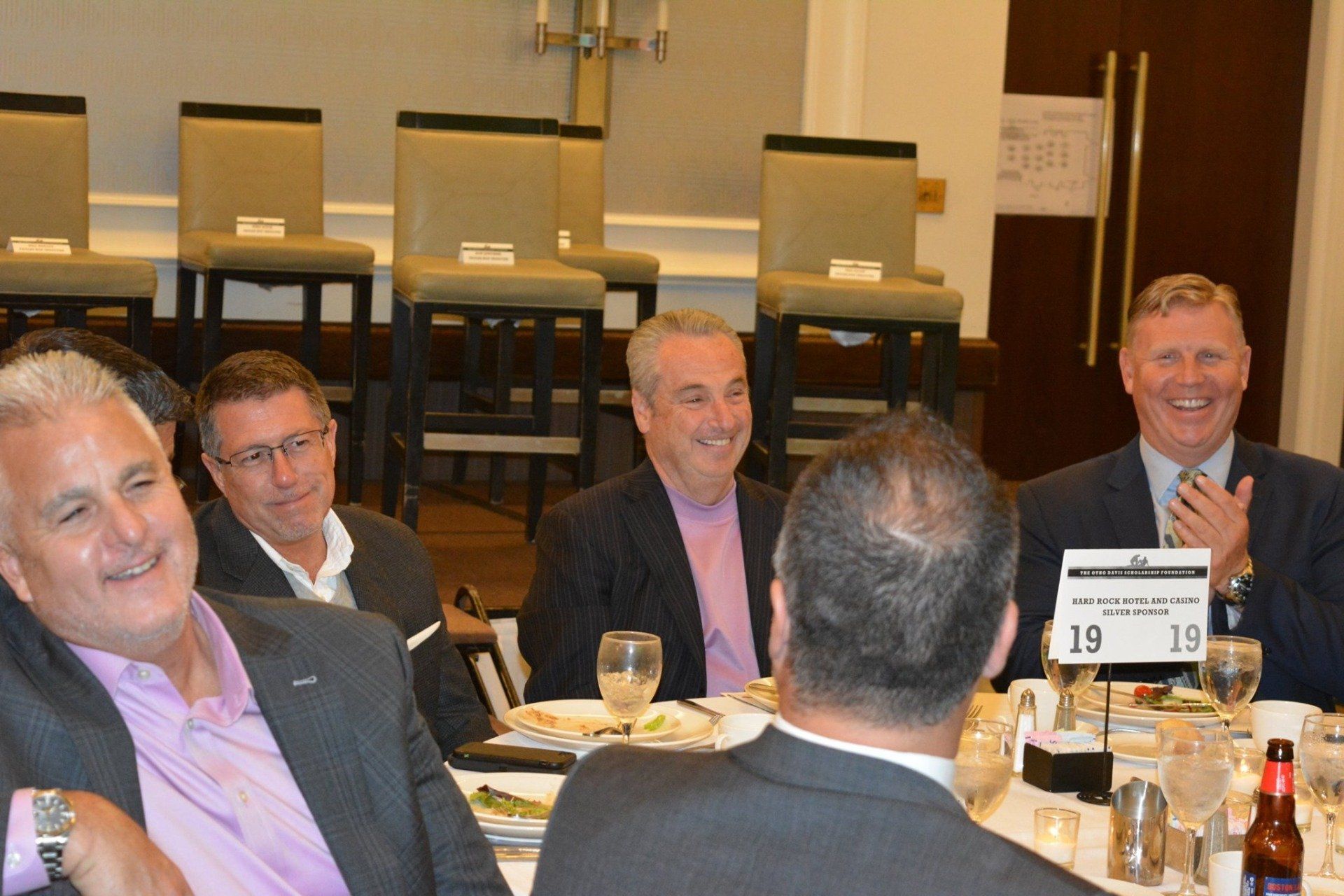 A group of men are sitting at a table with plates of food and drinks.