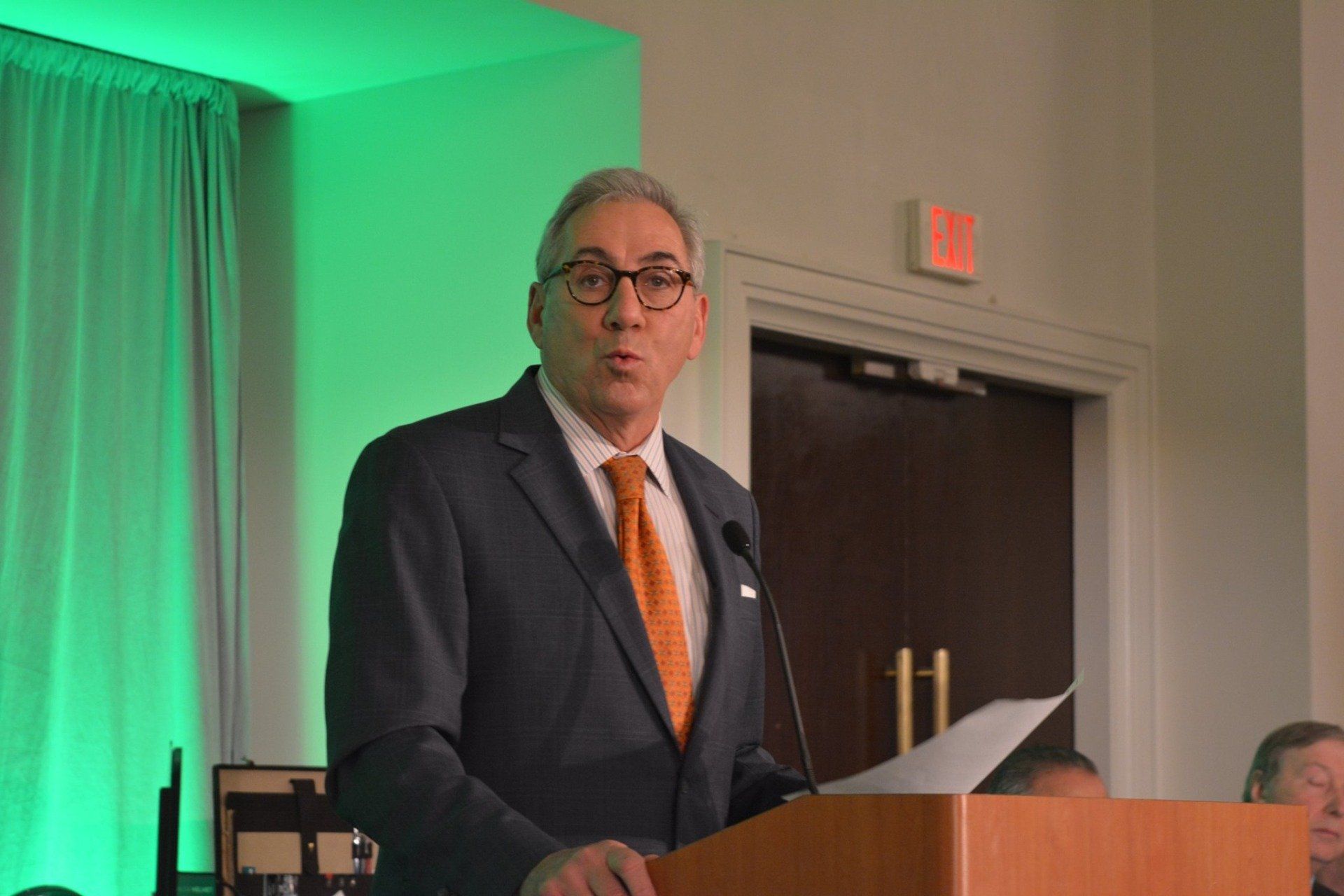 A man in a suit and tie is standing at a podium giving a speech.
