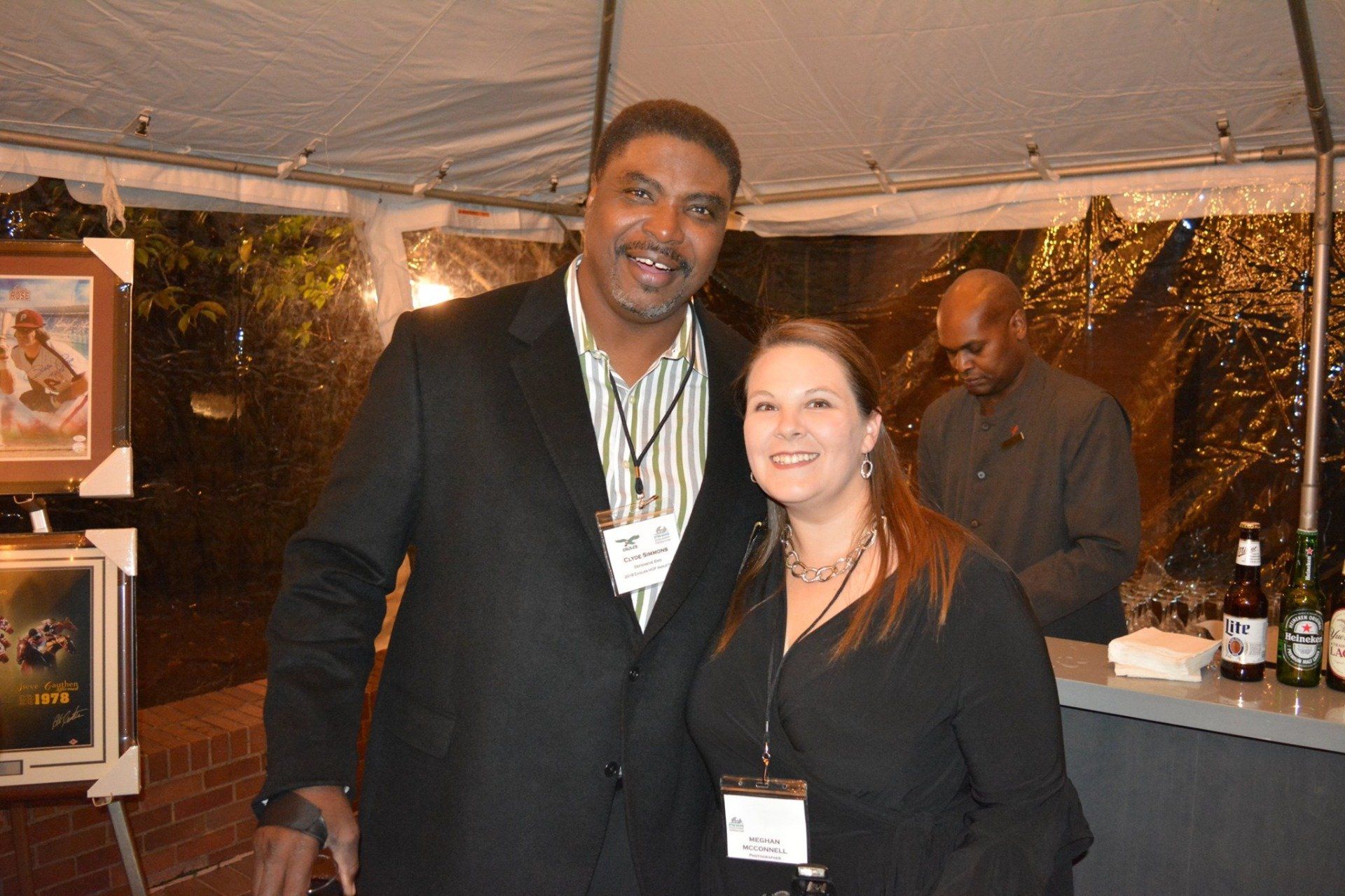 A man and a woman are posing for a picture under a tent.
