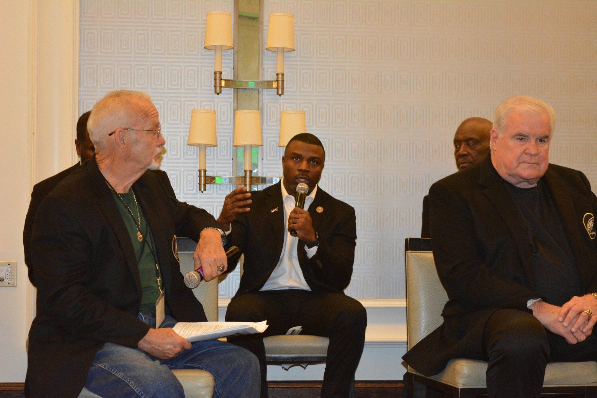 A group of men are sitting in chairs and talking to each other.