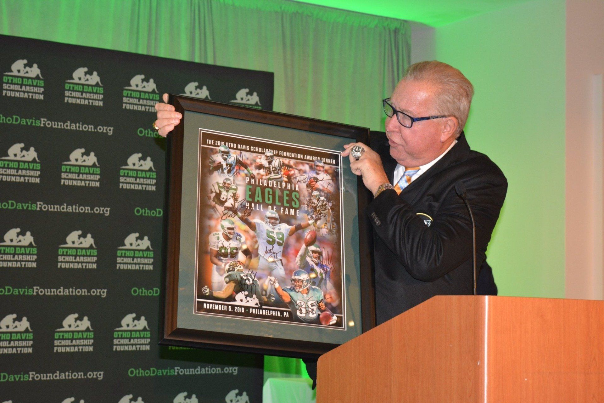 A man is holding a framed picture in front of a podium.