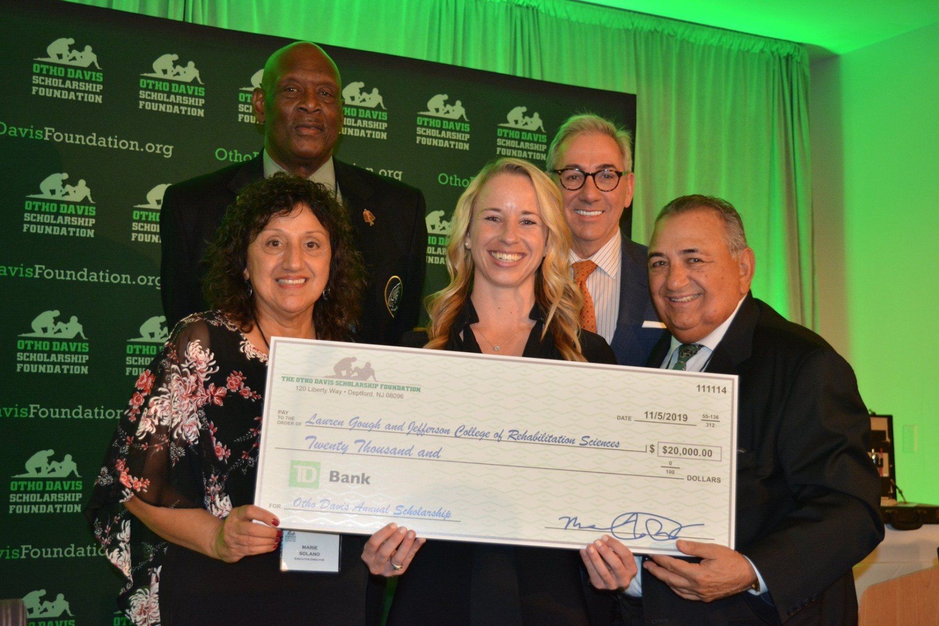 A group of people are posing for a picture while holding a large check.