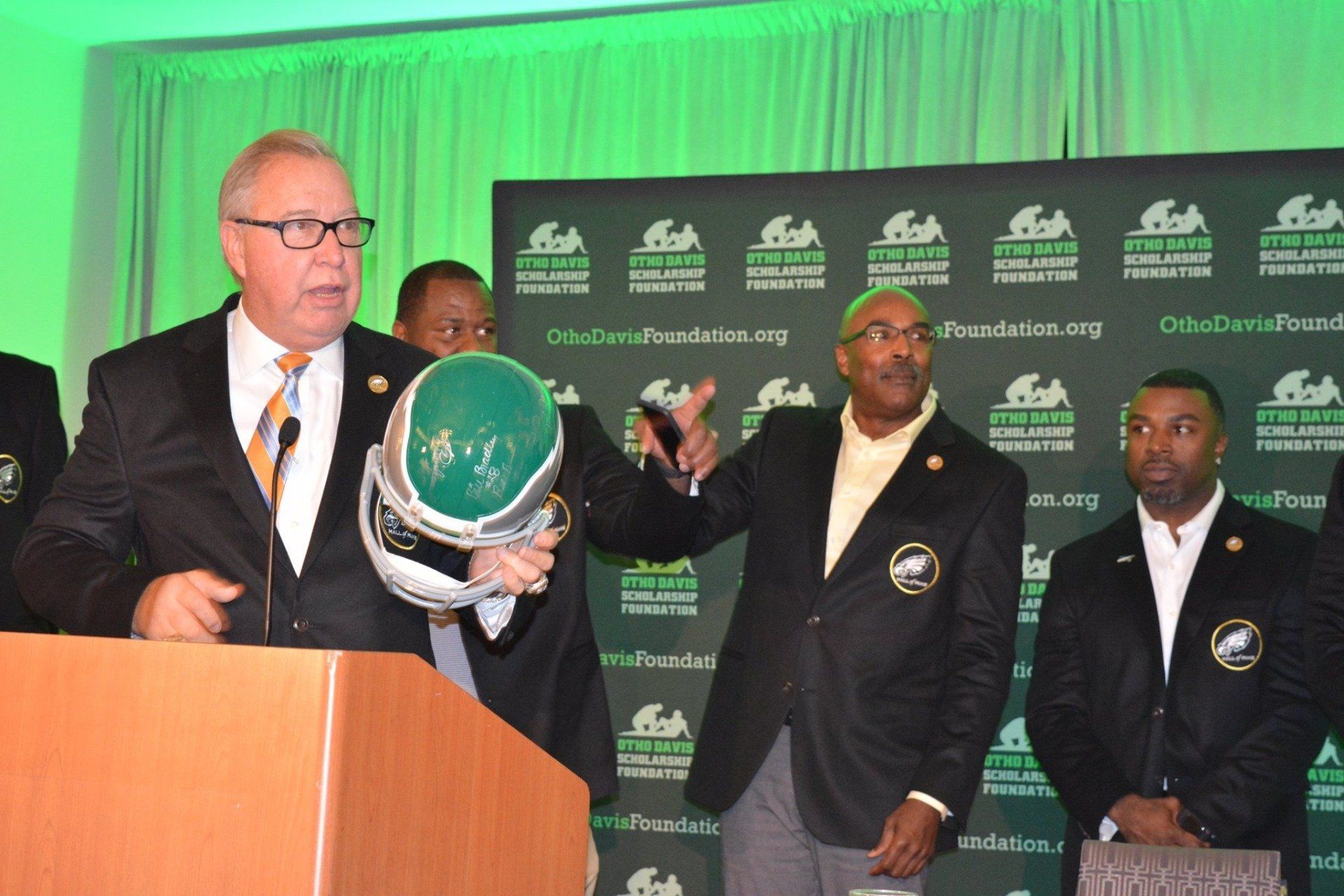 A group of men are standing around a podium holding a helmet.