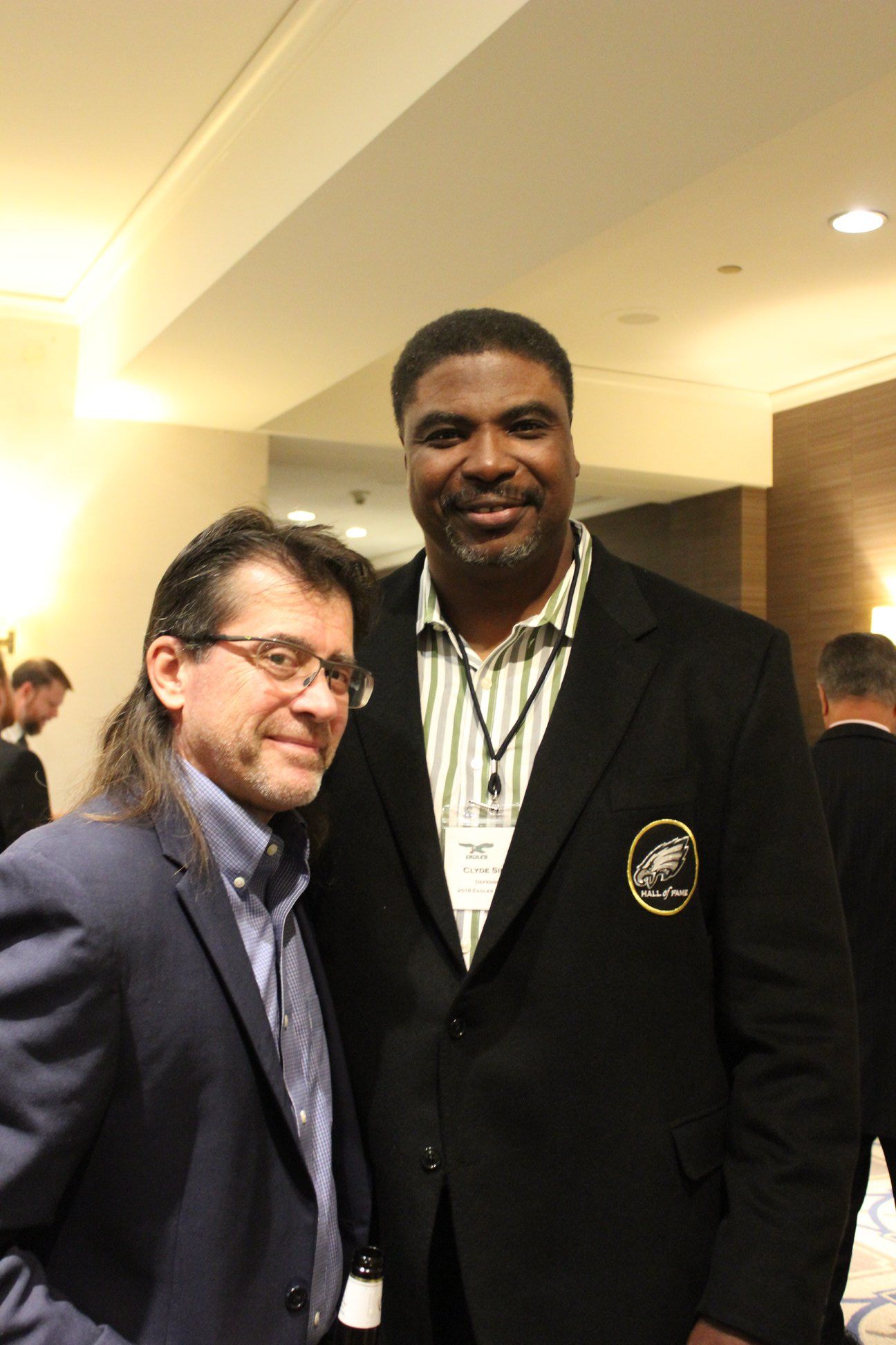 Two men in suits are posing for a picture in a room.