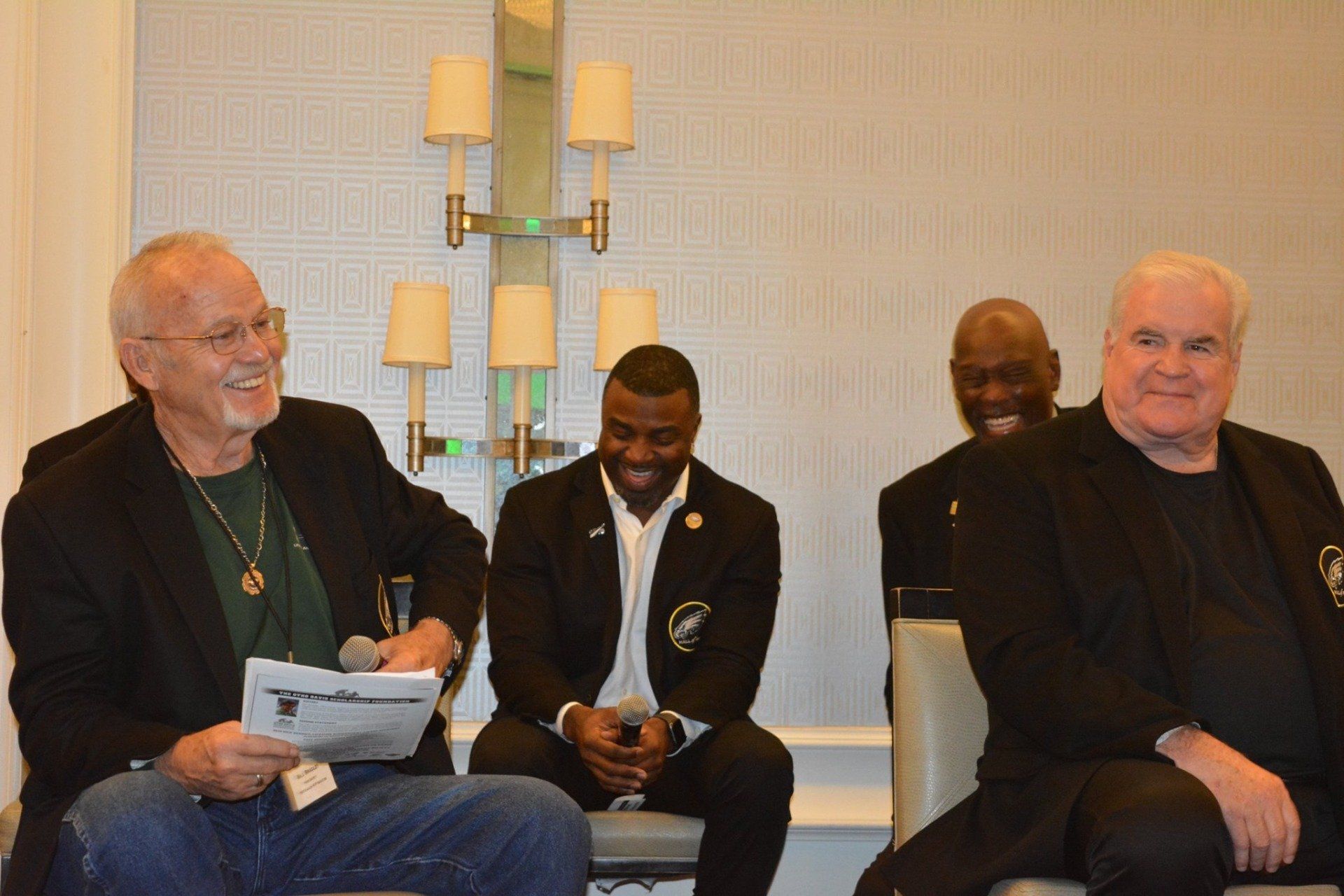 A group of men are sitting in chairs talking to each other.