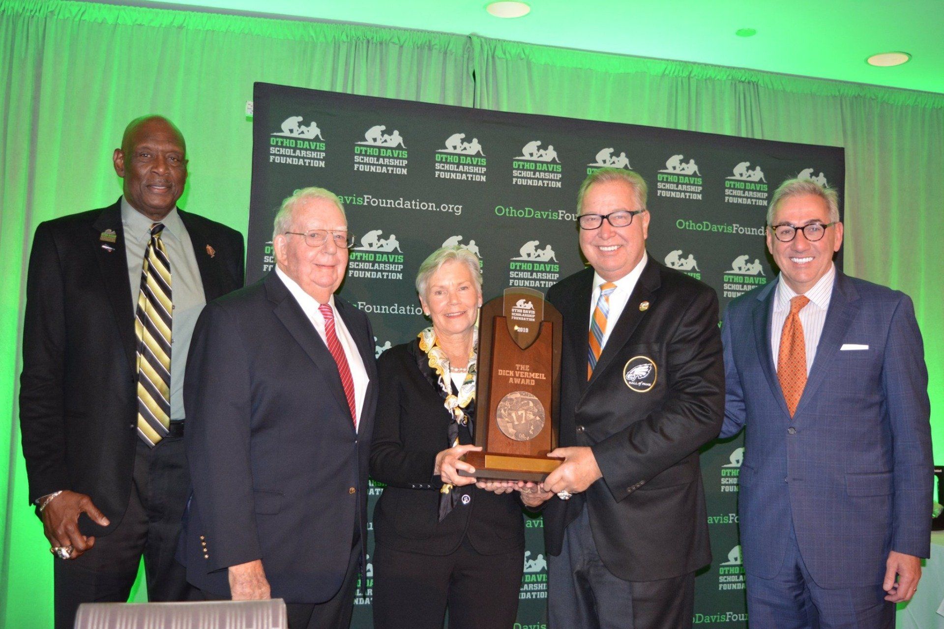 A group of men in suits and ties holding a trophy